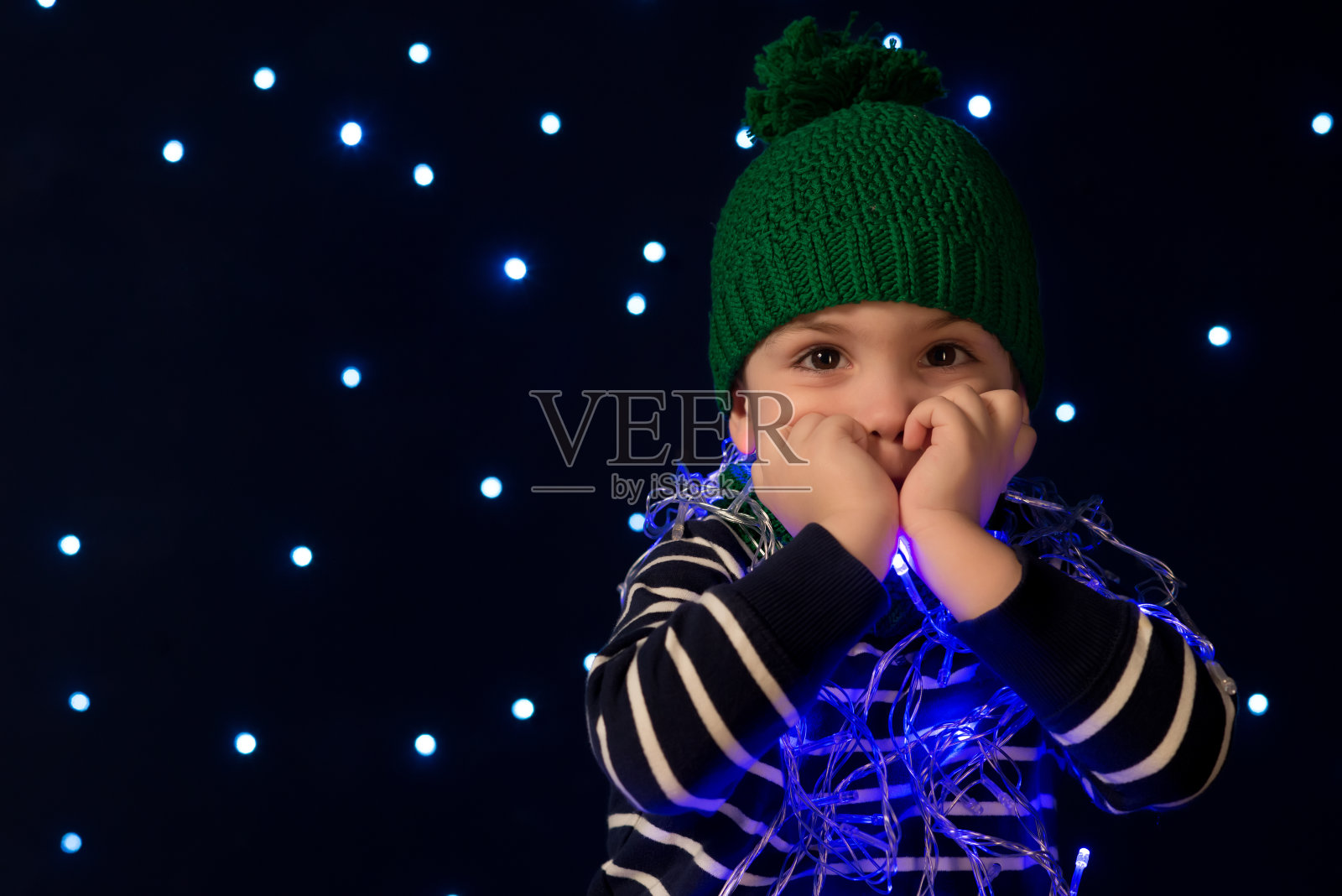 圣诞夜，小男孩站在屋顶上，天上挂着一颗闪亮的星星。照片摄影图片