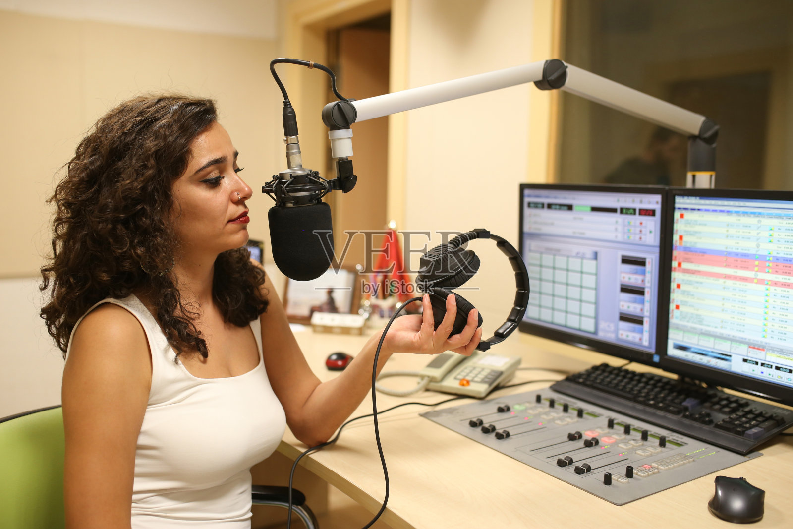 女主播通过麦克风在演播室播音的侧视图照片摄影图片