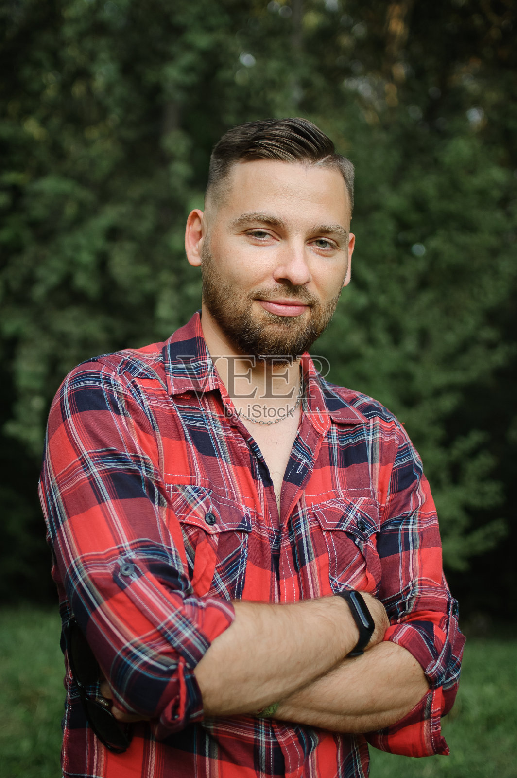 户外肖像轻松英俊的年轻人与胡子在公园的绿树背景。潮人风格的概念。照片摄影图片