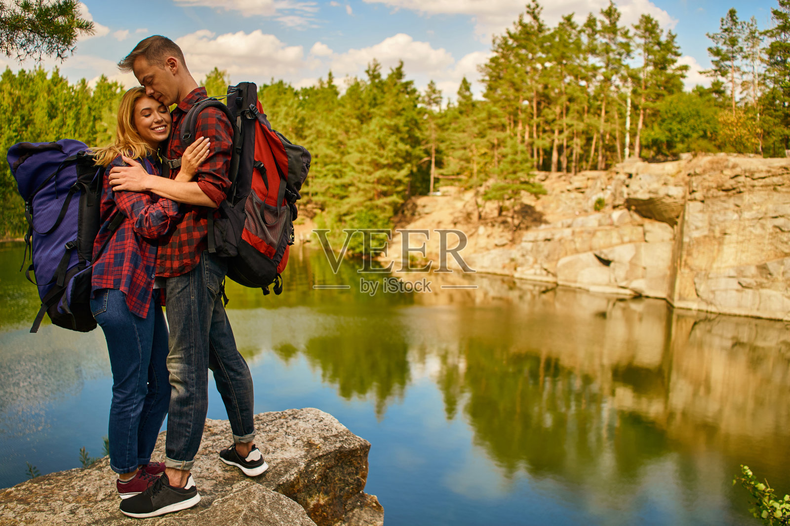 两个游客在探索一个新地方。一对英俊的夫妇与背包在自然附近的湖在森林背景。照片摄影图片