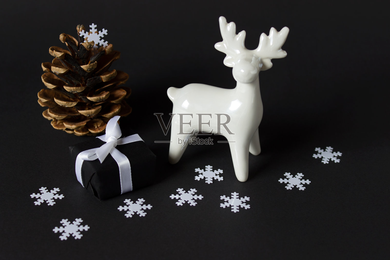 白色的驯鹿、木松果和黑色背景上的白色雪花照片摄影图片