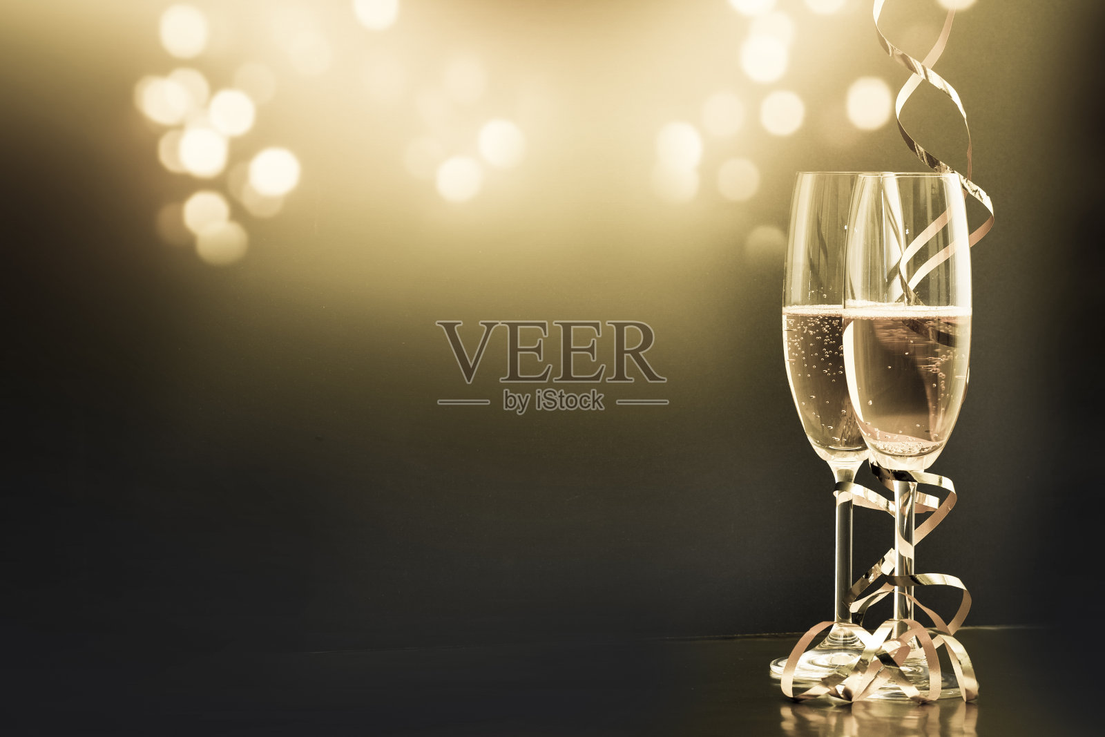 两个带着彩带的香槟酒杯，映衬着节日的灯光和烟花——新年庆祝活动照片摄影图片