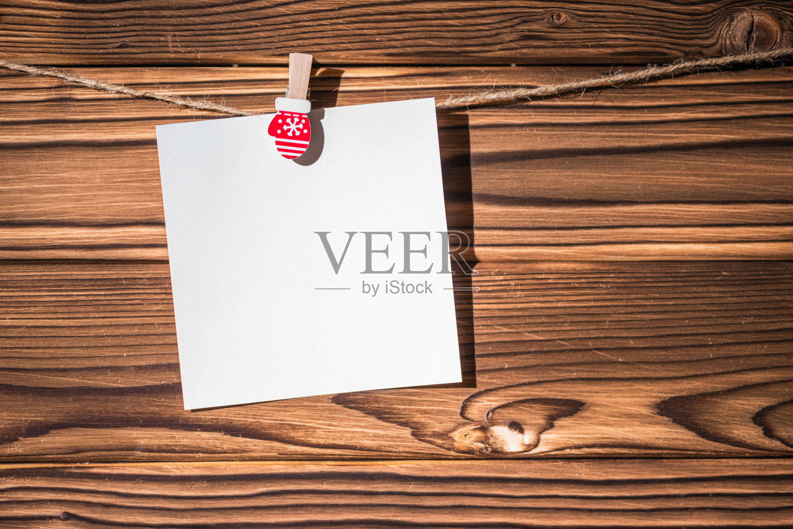 可爱的空牛皮纸小花环挂在绳子上的木制晾衣夹。乡村的圣诞装饰。副本的空间。木板的背景照片摄影图片