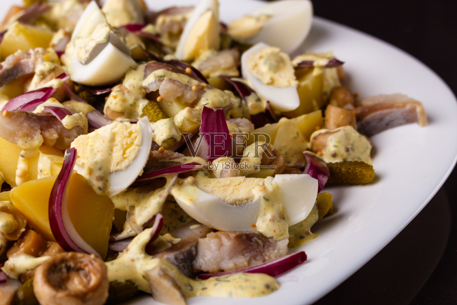有鸡蛋、洋葱、土豆和调味汁的沙拉照片摄影图片