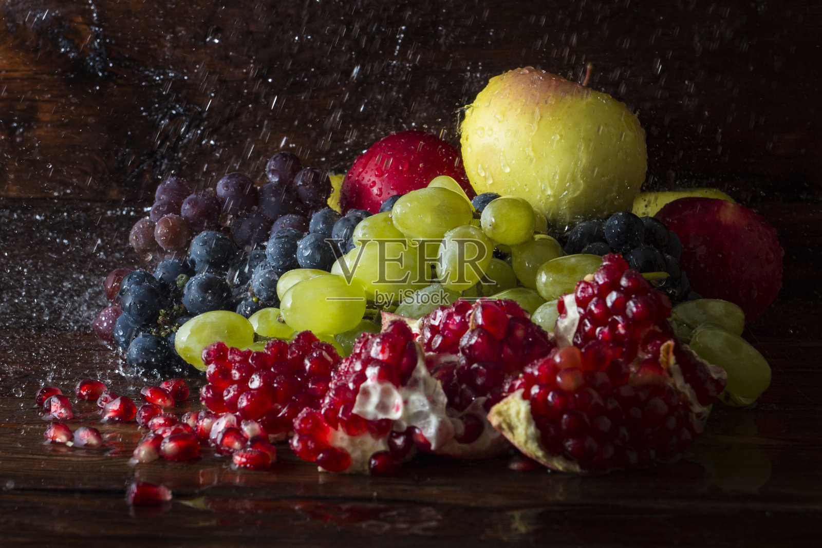 几个品种的葡萄，石榴，石榴籽，苹果在木背景与水溅。新鲜水果概念，新作物照片摄影图片