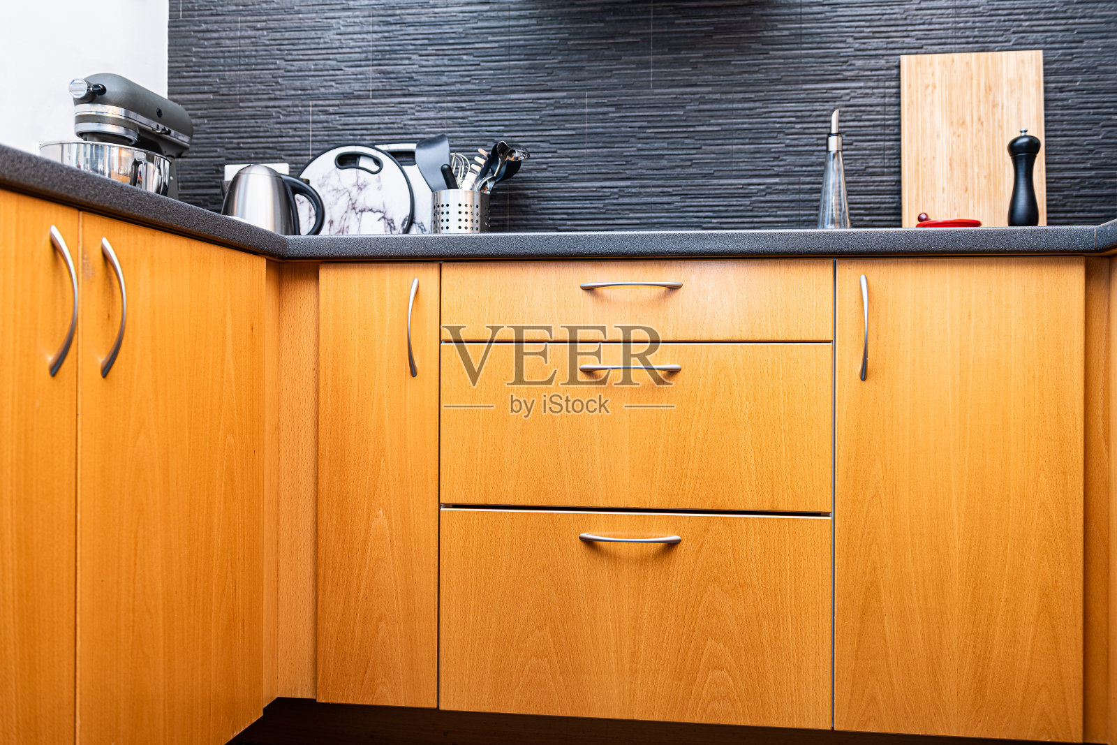 现代的木制厨房抽屉橱柜与钢把手和后挡板与器具，设备和切菜板没有人照片摄影图片