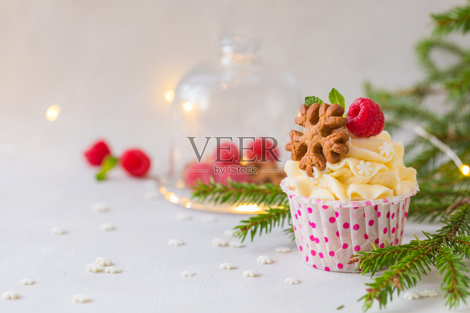 圣诞纸杯蛋糕或松饼，奶油和覆盆子，在冷杉树枝的背景照片摄影图片