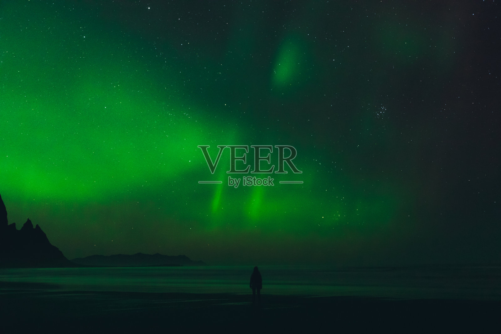 在冰岛山景城美丽的海滩上享受北极光的女人剪影照片摄影图片