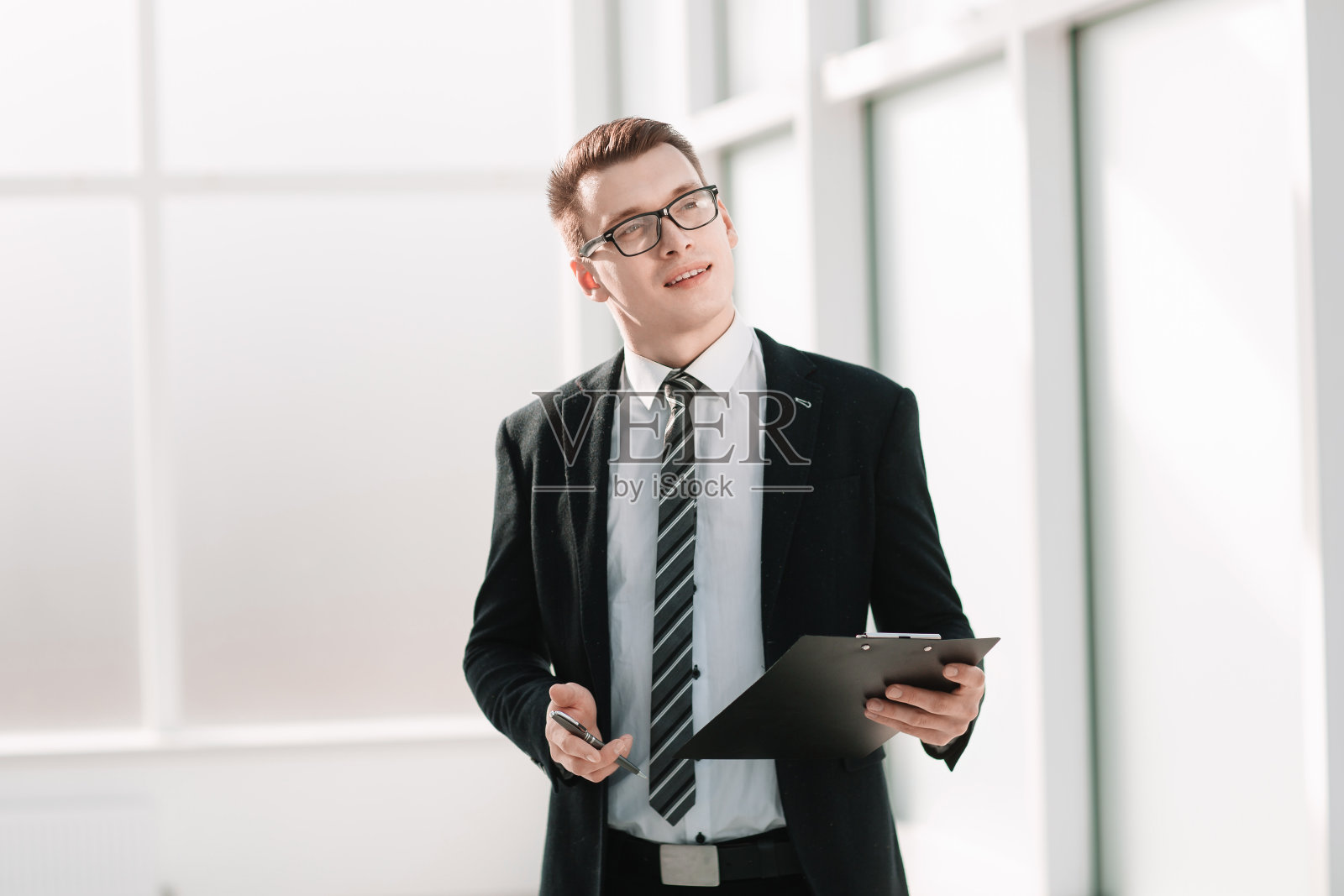 成功的年轻企业家站在办公室里。照片摄影图片