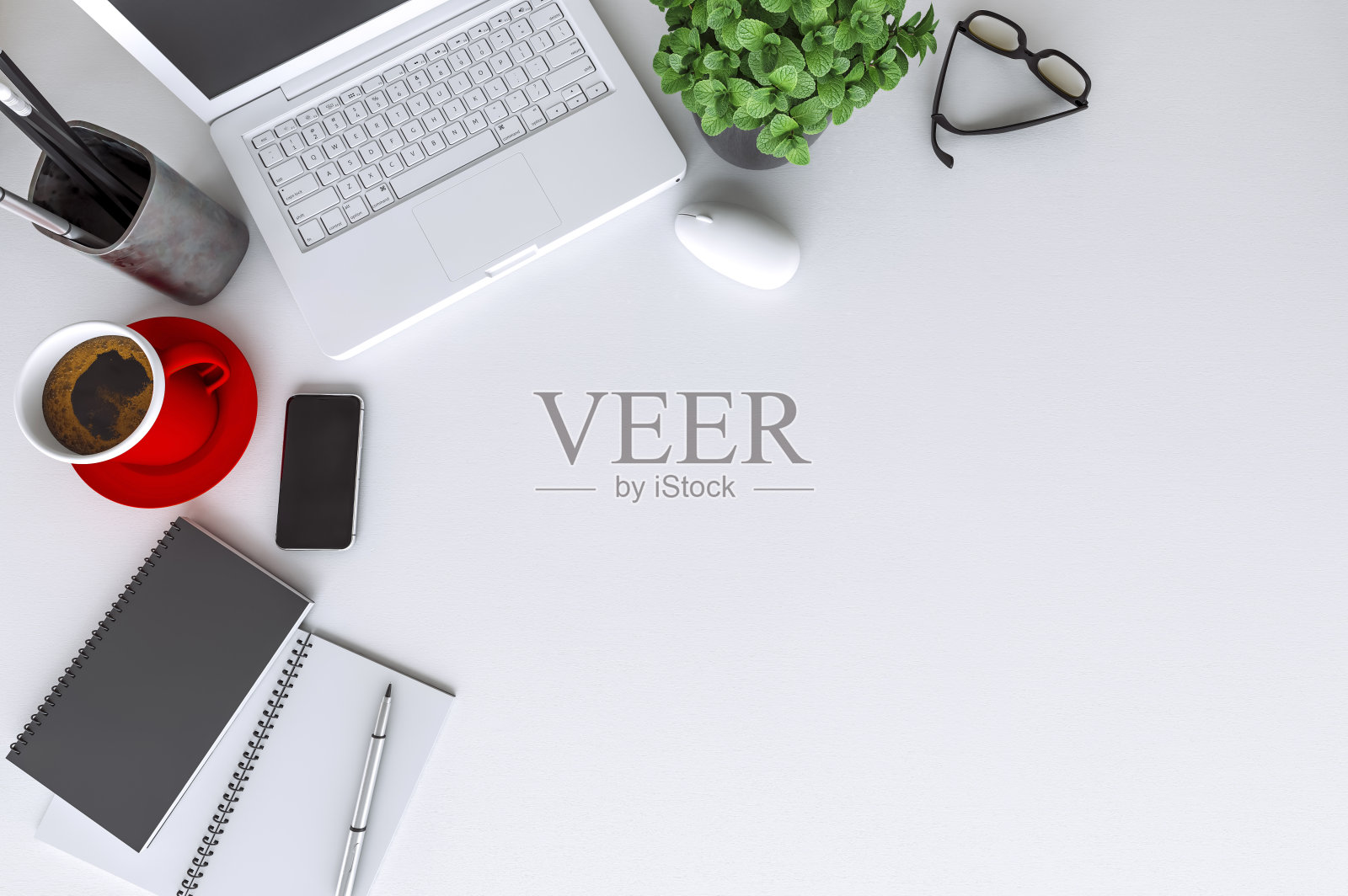 配有笔记本电脑的现代白色办公桌边，黑色屏幕的智能手机上方是一台笔记本电脑和一杯咖啡照片摄影图片