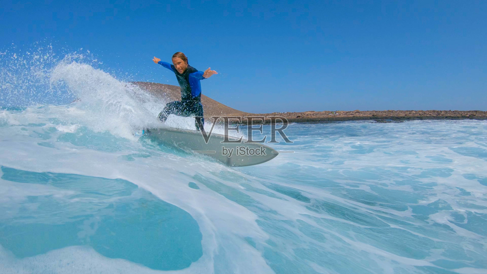 低角度视图:酷男性冲浪者在他的乐趣冲浪板上做一个快速的急转弯。照片摄影图片