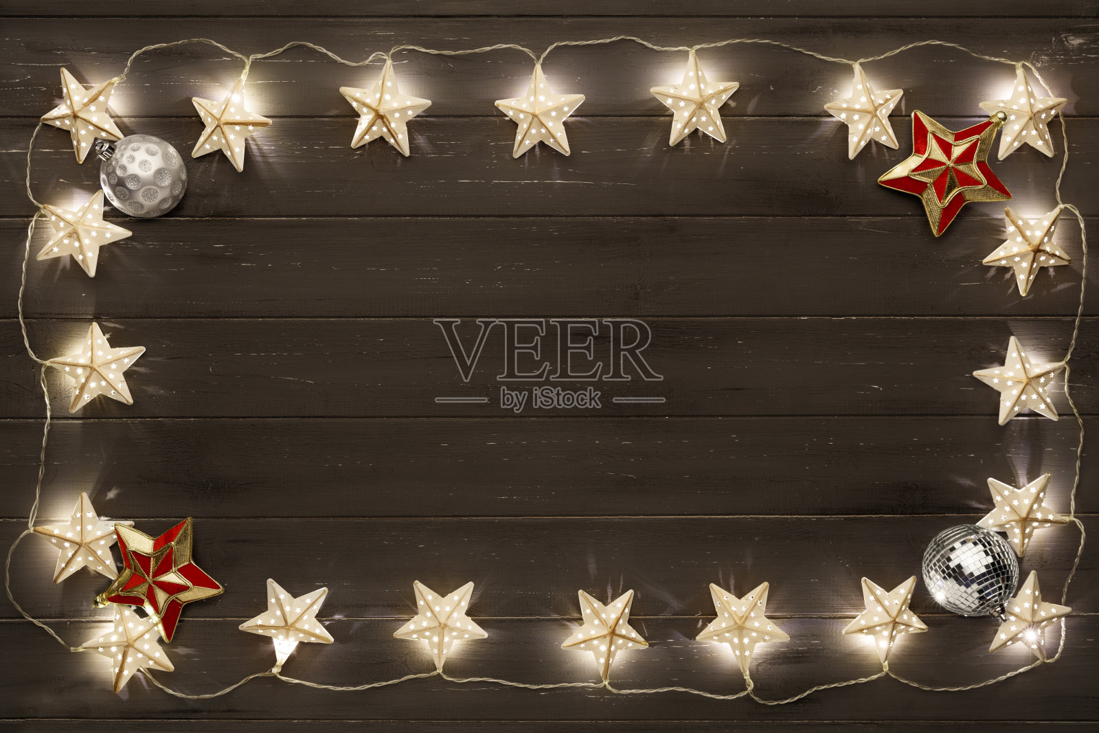 一圈金色的星星圣诞彩灯和圣诞装饰品，放在一块破旧的深色木板上照片摄影图片