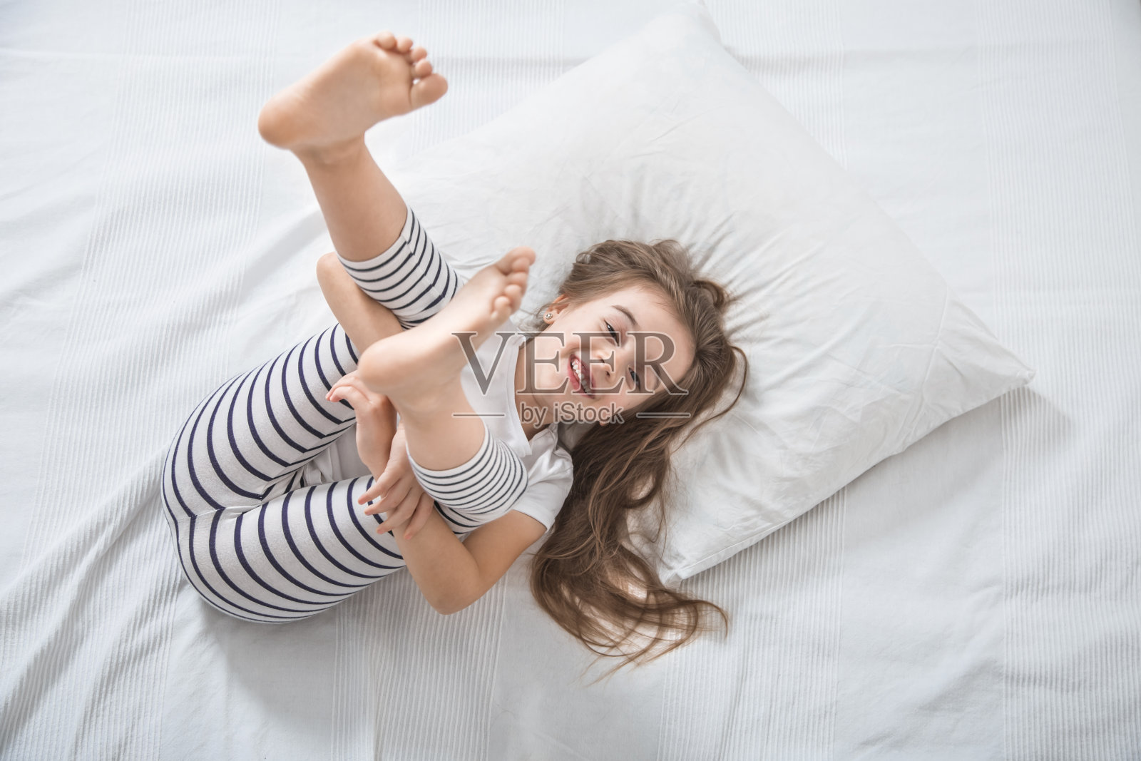 可爱的小女孩早上在床上醒来。照片摄影图片