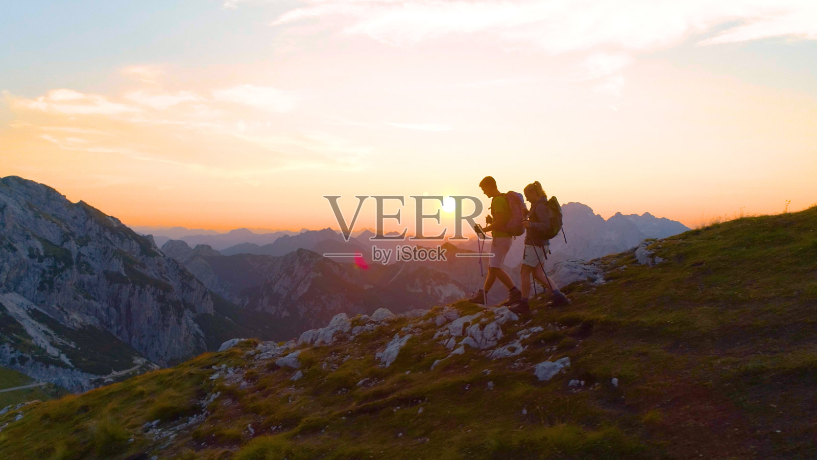 镜头光晕:日出时分，活跃的女人和男友下山。照片摄影图片