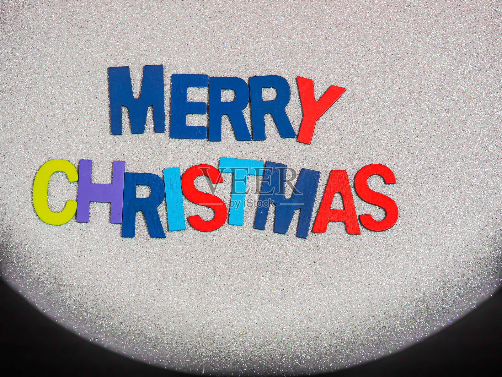 顶视图或直接上方的彩色木制字母的圣诞文字粗糙的梯度闪闪发光的白纸纹理和黑色的背景。圣诞贺卡。照片摄影图片