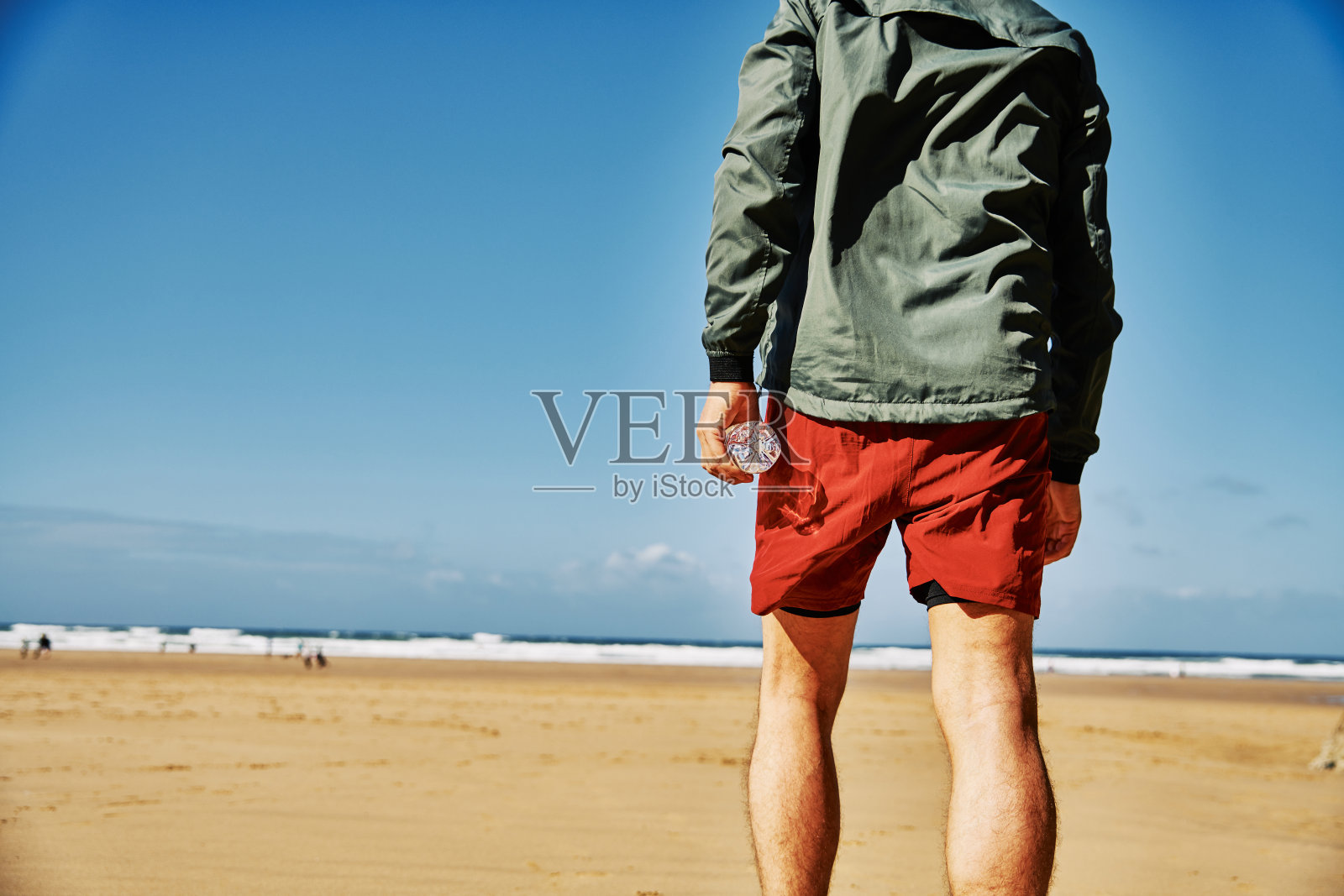 一个阳光明媚的秋日，穿着运动服的男子在Perranporth海滩上准备跑步。照片摄影图片