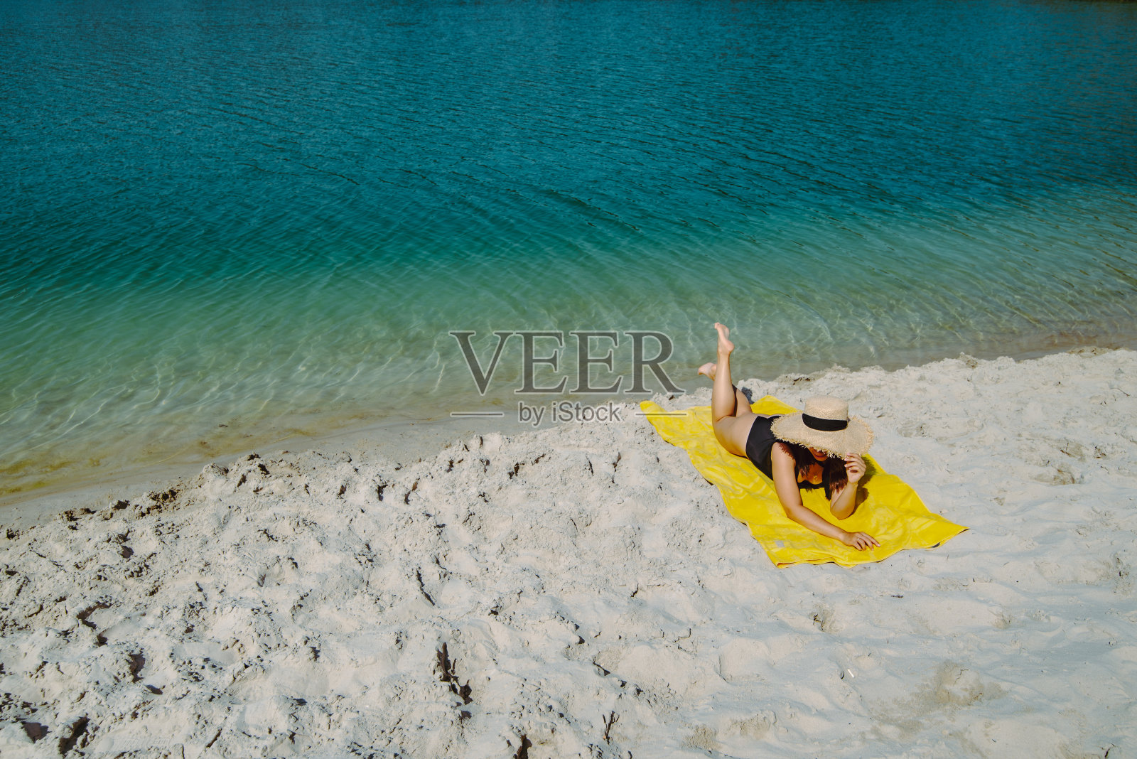 女人躺在黄色毯子上日光浴在沙滩度假概念照片摄影图片