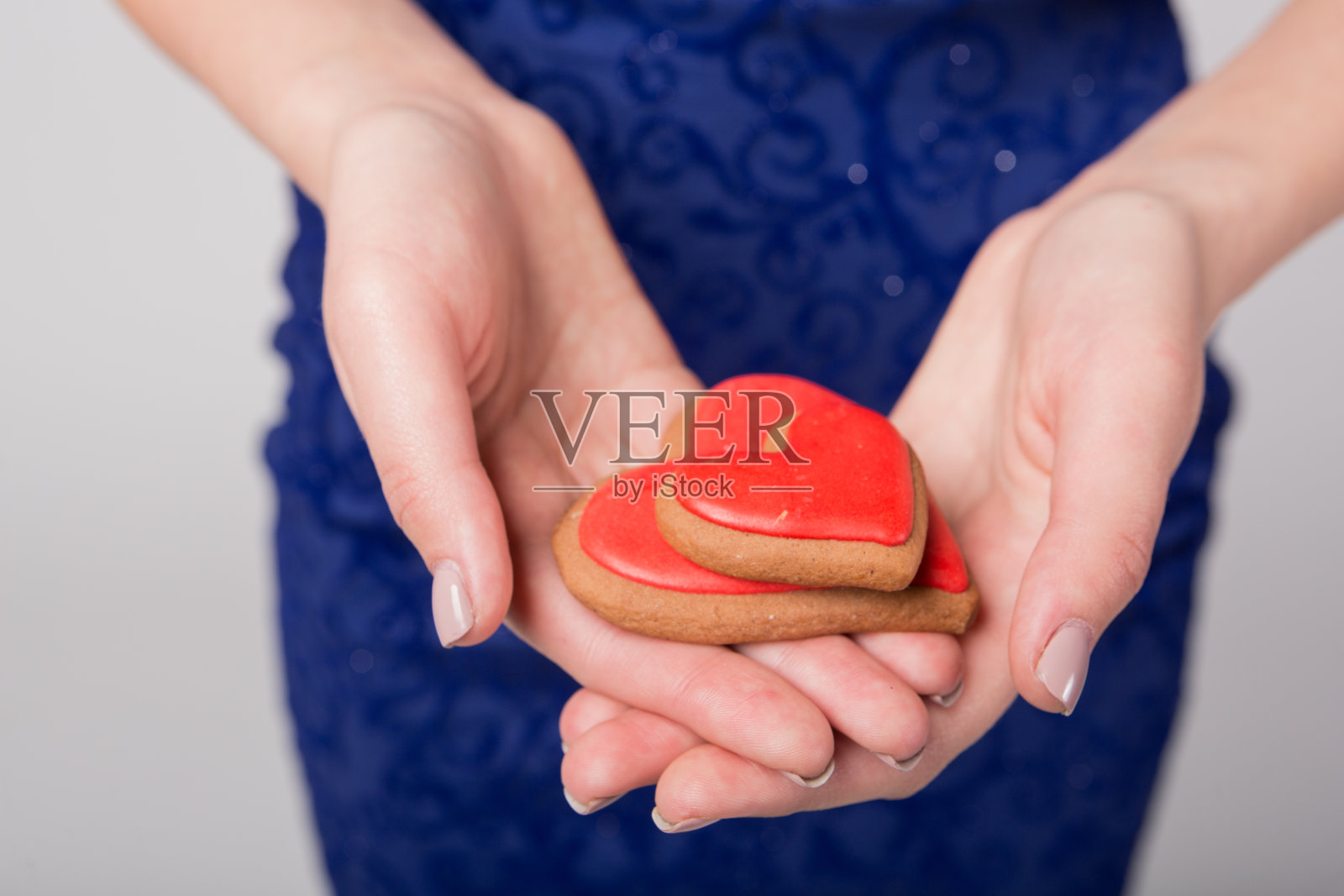 在女孩的手掌是两个红心形状的饼干，爱情的概念，友谊和约会，微距摄影照片摄影图片