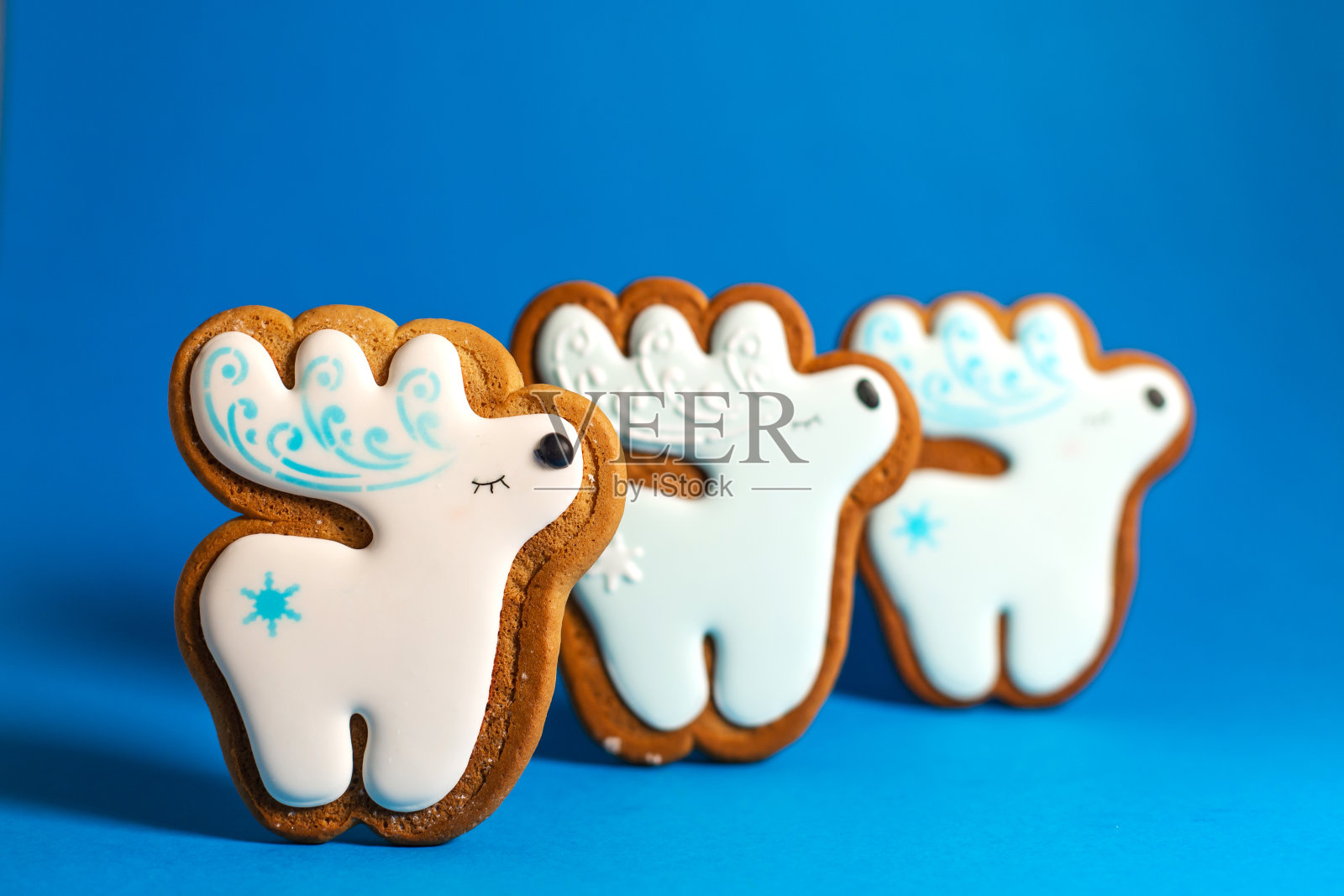 姜饼饼干可爱的鹿在蓝色的背景。传统的圣诞食物。圣诞节和新年假期概念。照片摄影图片