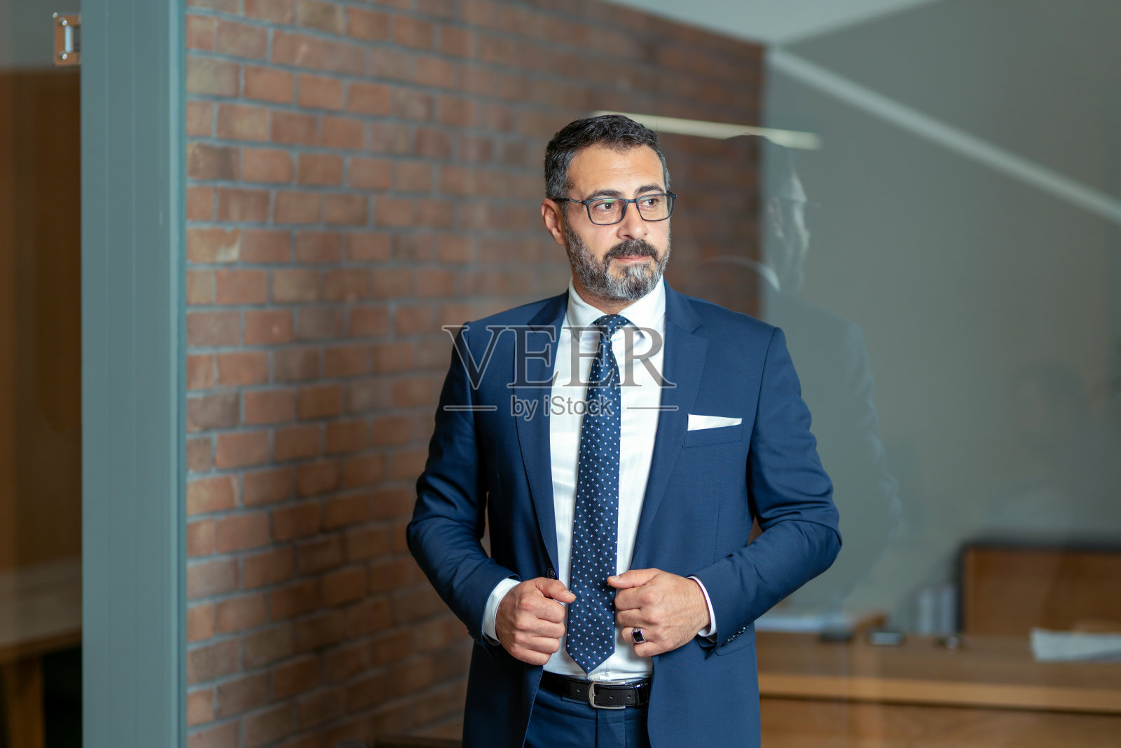 一位戴着眼镜、魅力十足的银行家穿着时髦的西装，高高兴兴地准备参加会议照片摄影图片