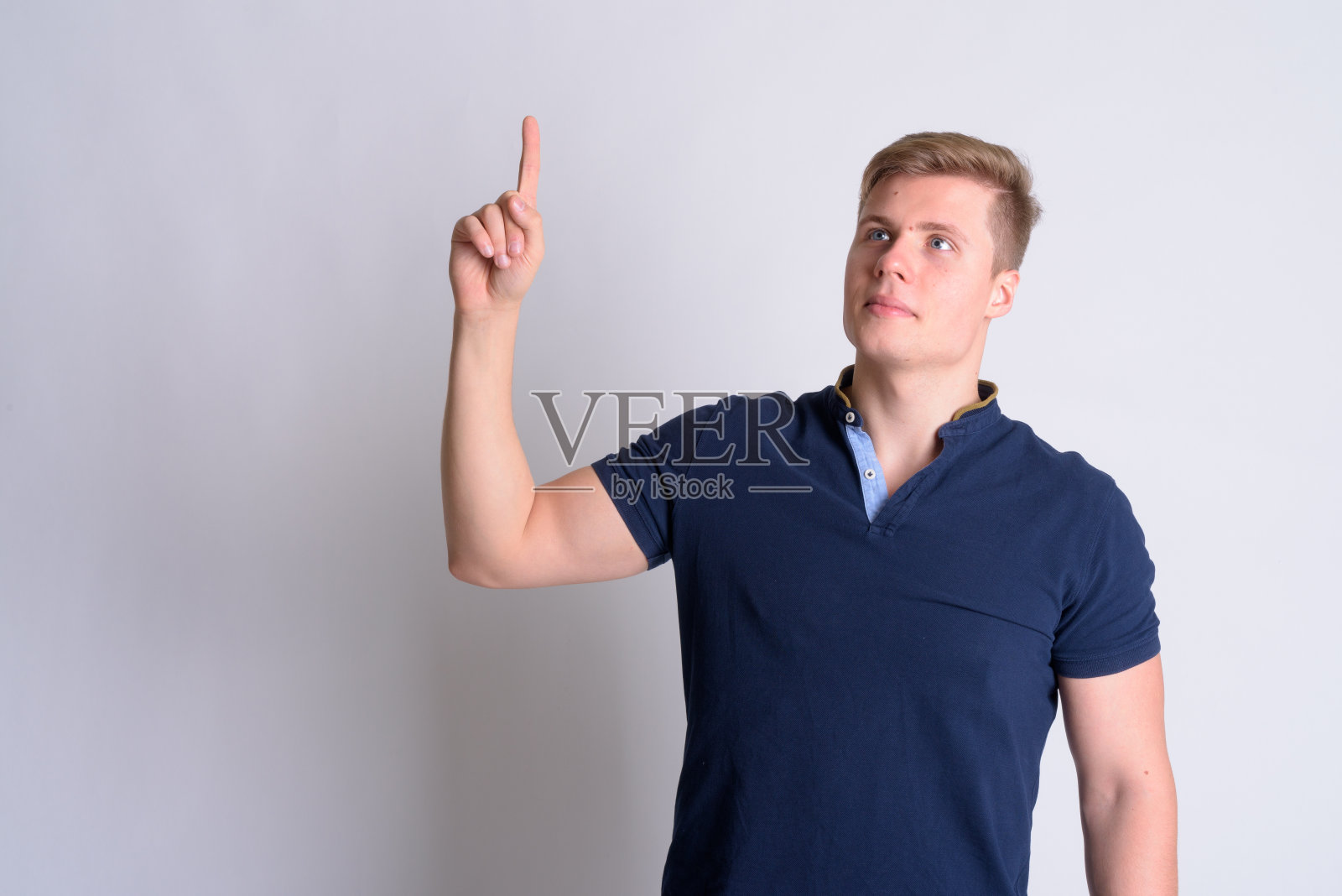 年轻的金发英俊男子的肖像思考和指着照片摄影图片