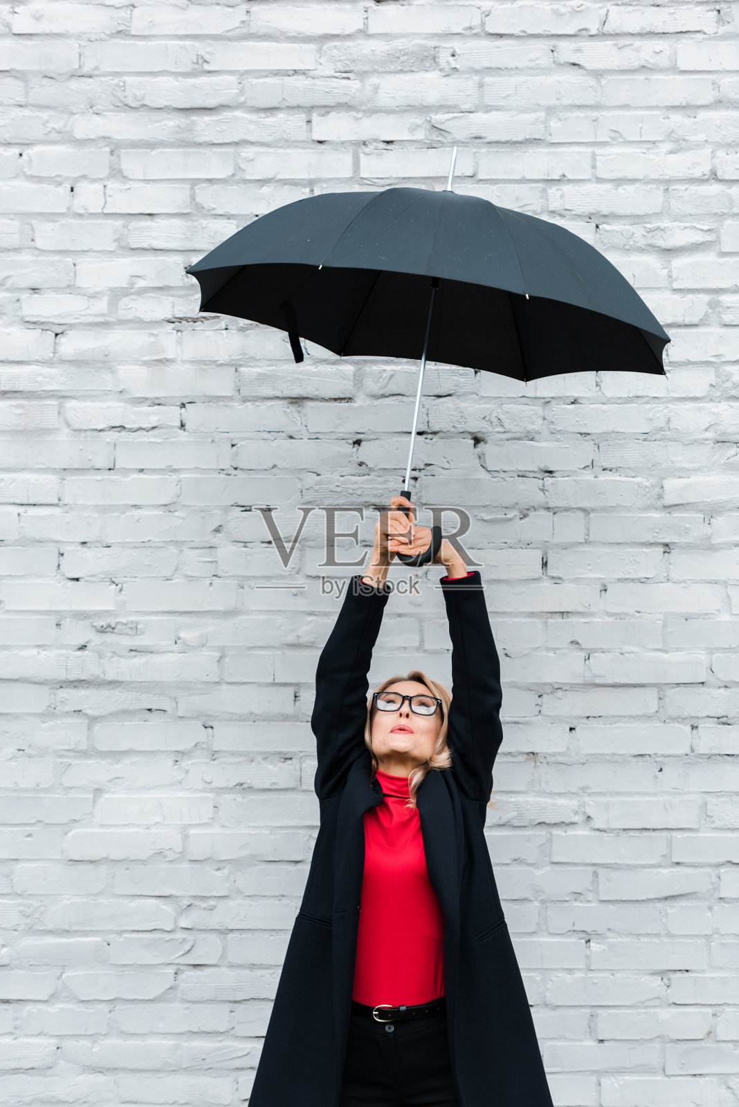 迷人的金发女商人穿着黑色外套拿着伞照片摄影图片