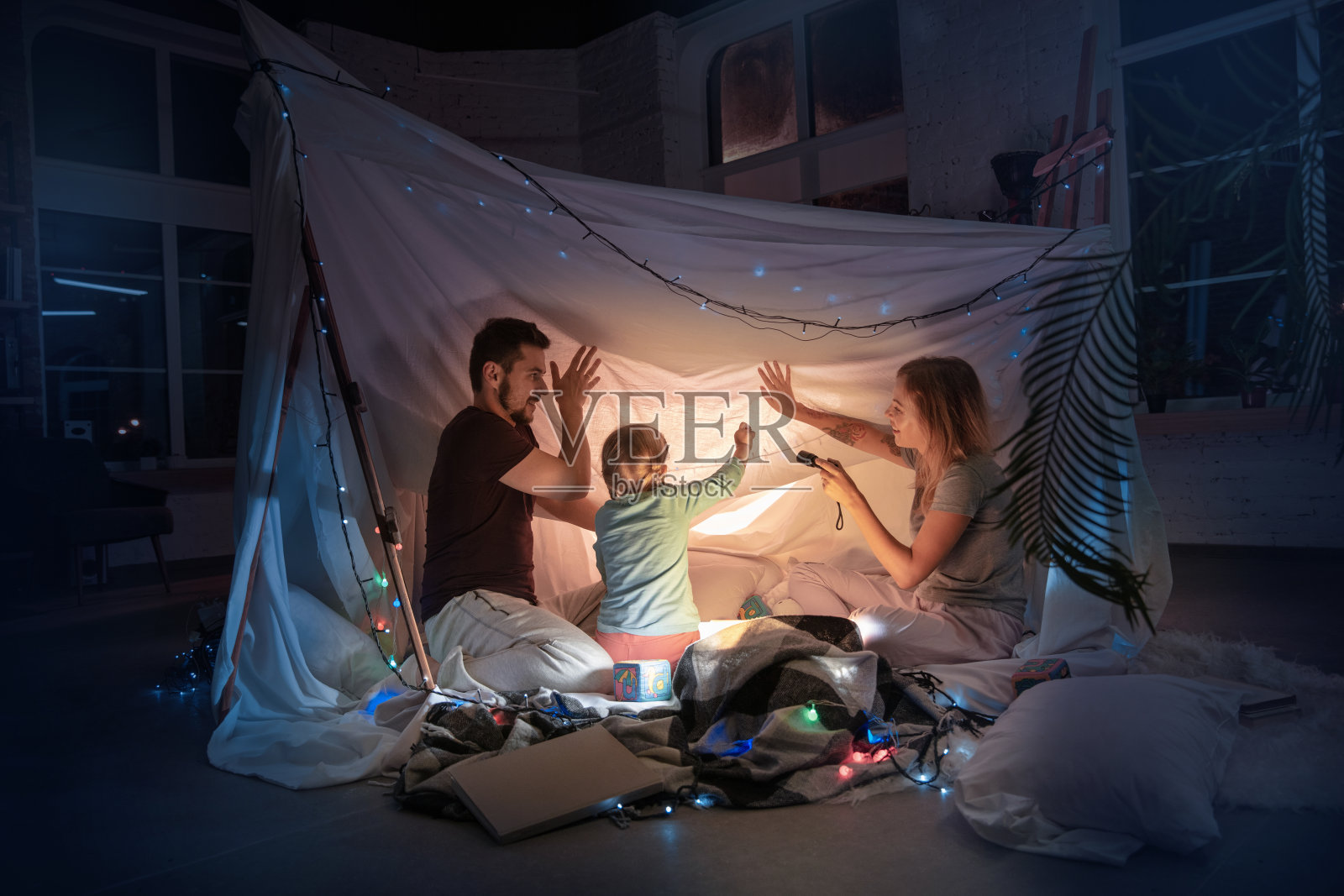 一家人坐在帐篷里，拿着手电筒读故事照片摄影图片