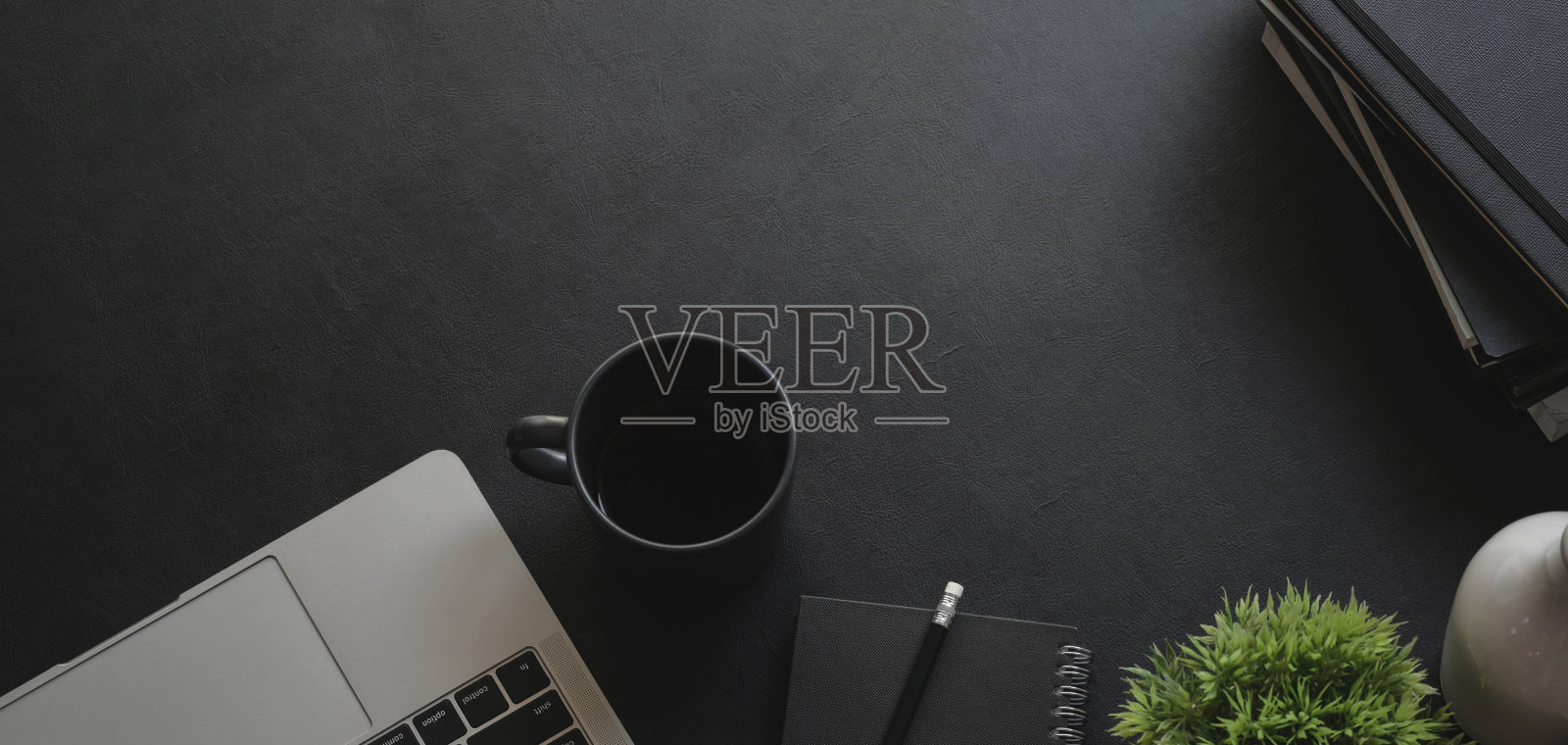 头顶拍摄的黑暗现代工作场所与笔记本电脑和办公用品在黑色的桌子上照片摄影图片