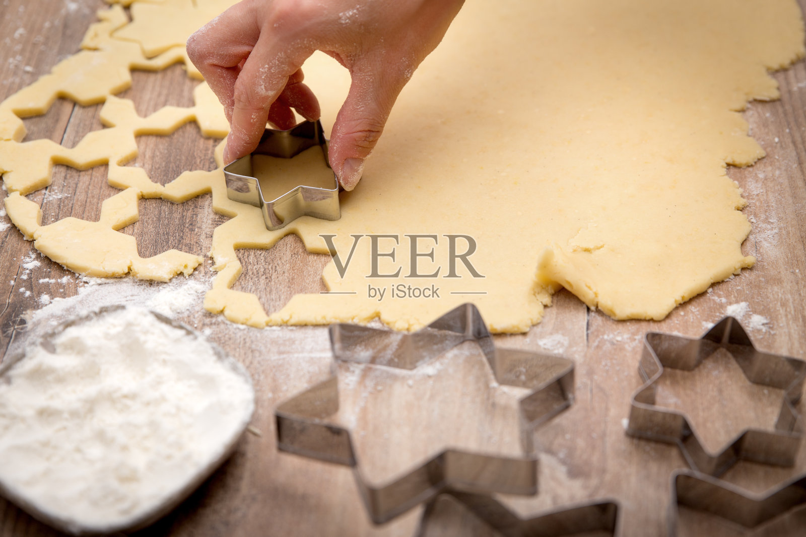 用星星形状的饼干切割机，面粉和明亮的饼干面团，女人正在切割照片摄影图片