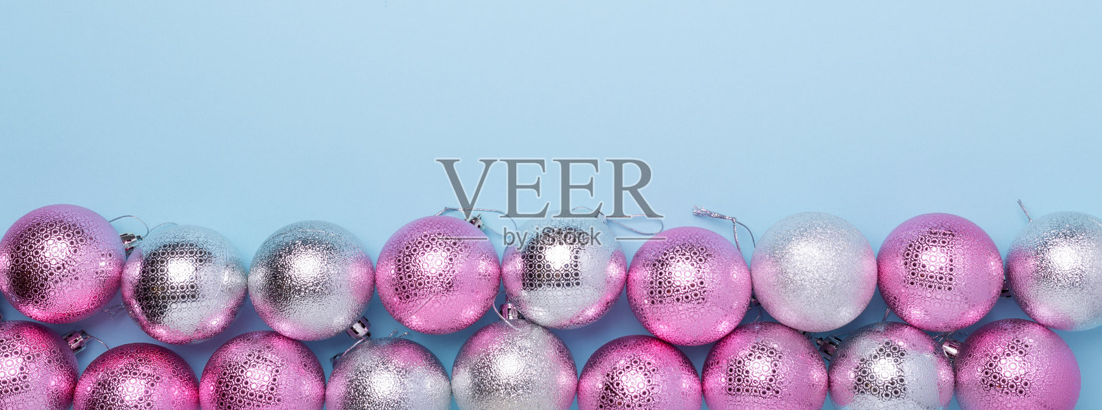 粉红色和银色的球在柔和的蓝色背景。网页横幅。圣诞节，冬天，新年的概念照片摄影图片