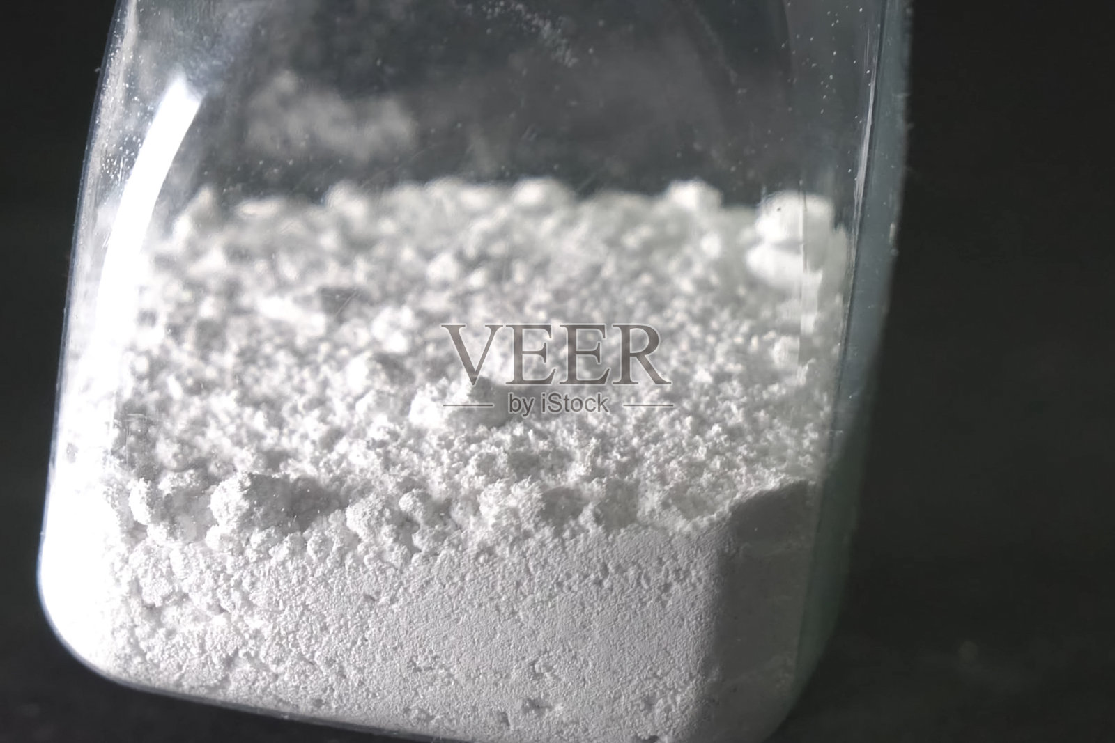 白色粉末置于透明瓶中。桌上有白色粉末。照片摄影图片