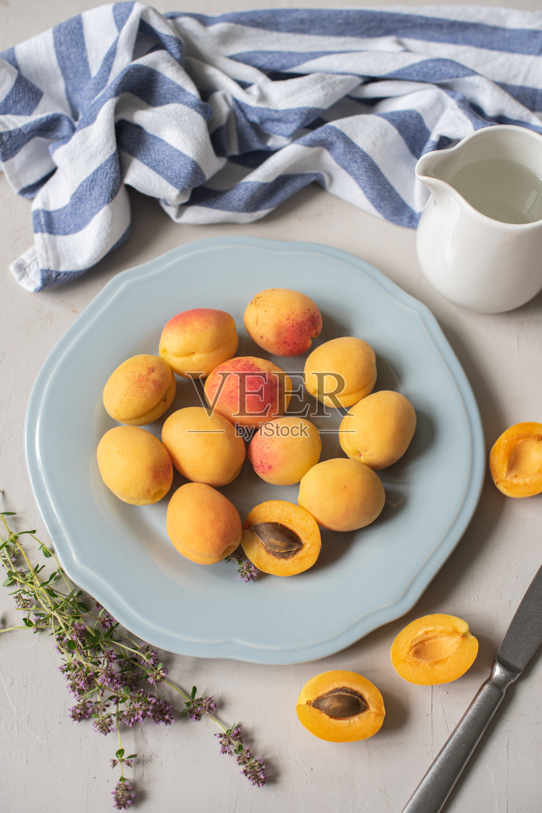 新鲜的有机杏子，整个和一半带骨的蓝色盘子照片摄影图片