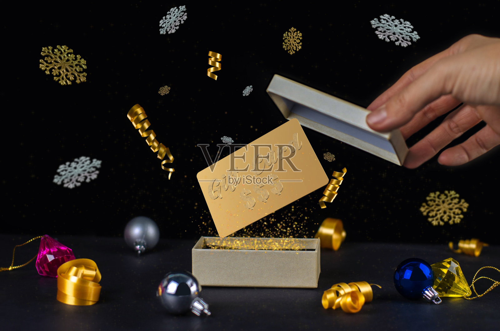 打开魔法圣诞礼盒的礼物，装饰，金色的灰尘，颗粒，丝带和金卡。新年的礼物照片摄影图片