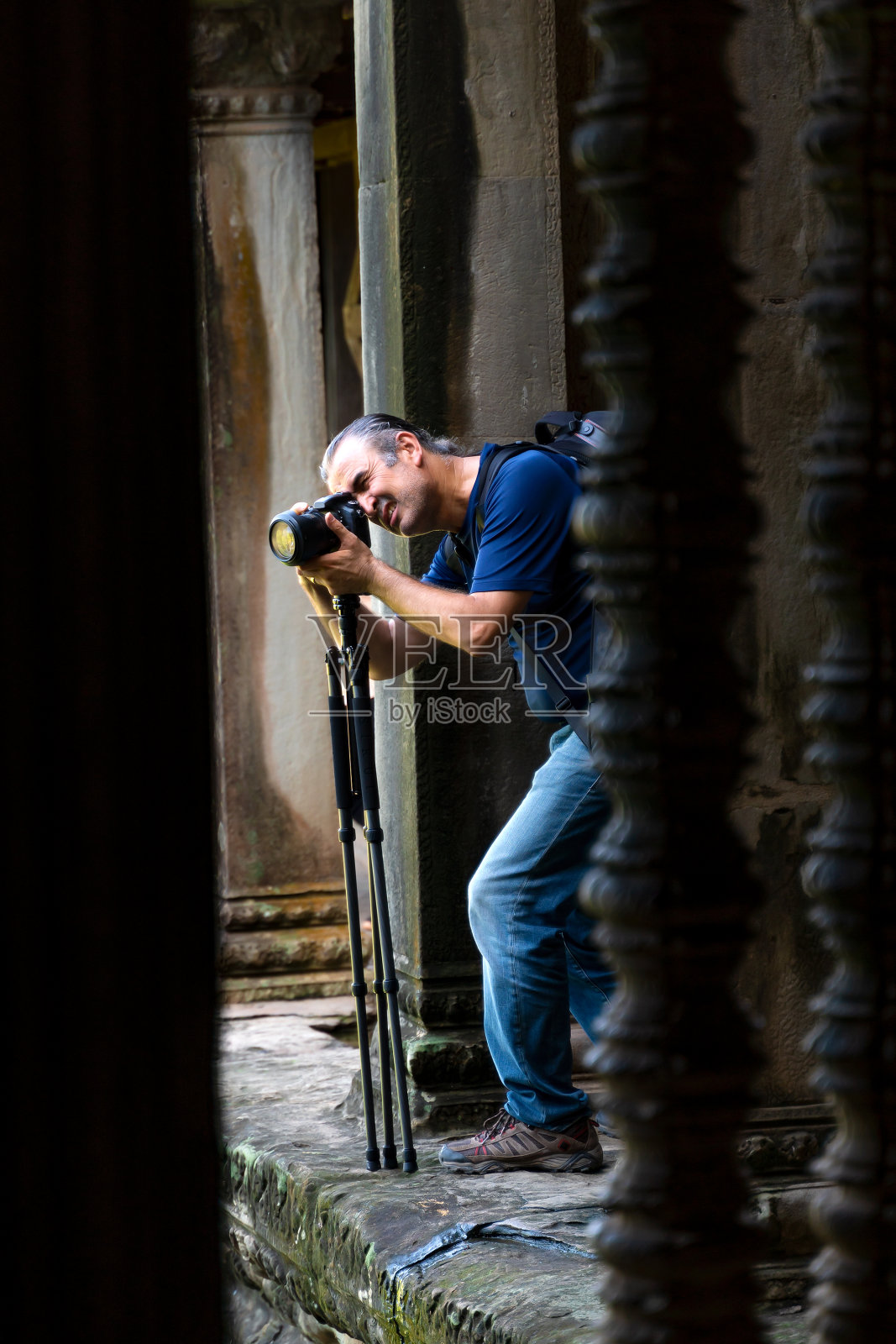 摄影师，在吴哥窟寺拍摄，在柱子后面与三脚架照片摄影图片