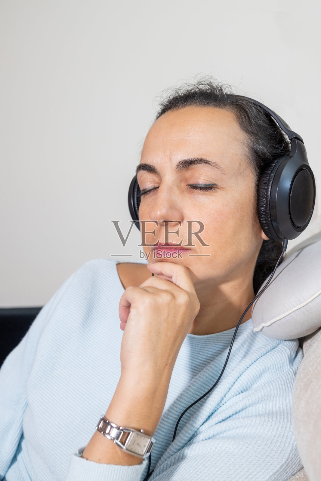 一个年轻的西班牙女人在家里用耳机听音乐照片摄影图片