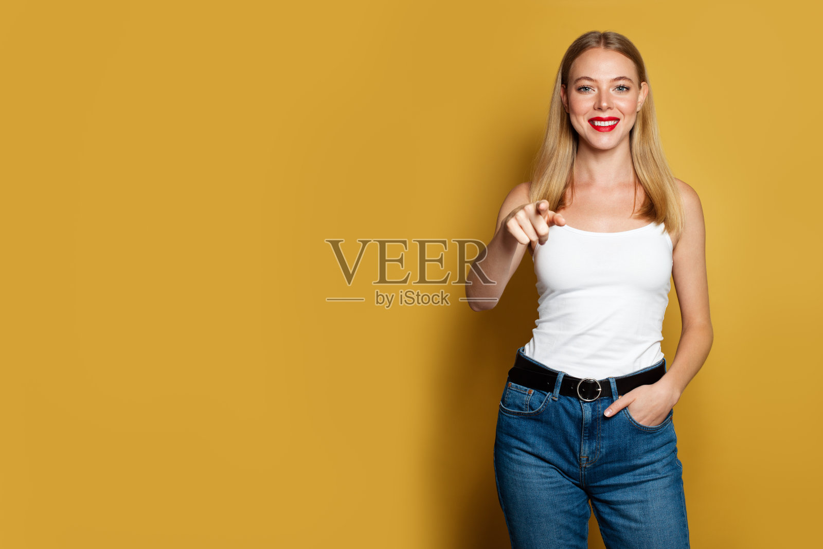 快乐的女人指着明亮的黄色背景。积极情绪照片摄影图片