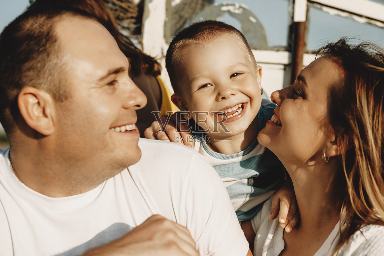 一个快乐的小男孩在和爸爸妈妈玩的时候看着镜头笑的特写。妈妈和爸爸和他们的孩子一起笑。照片摄影图片