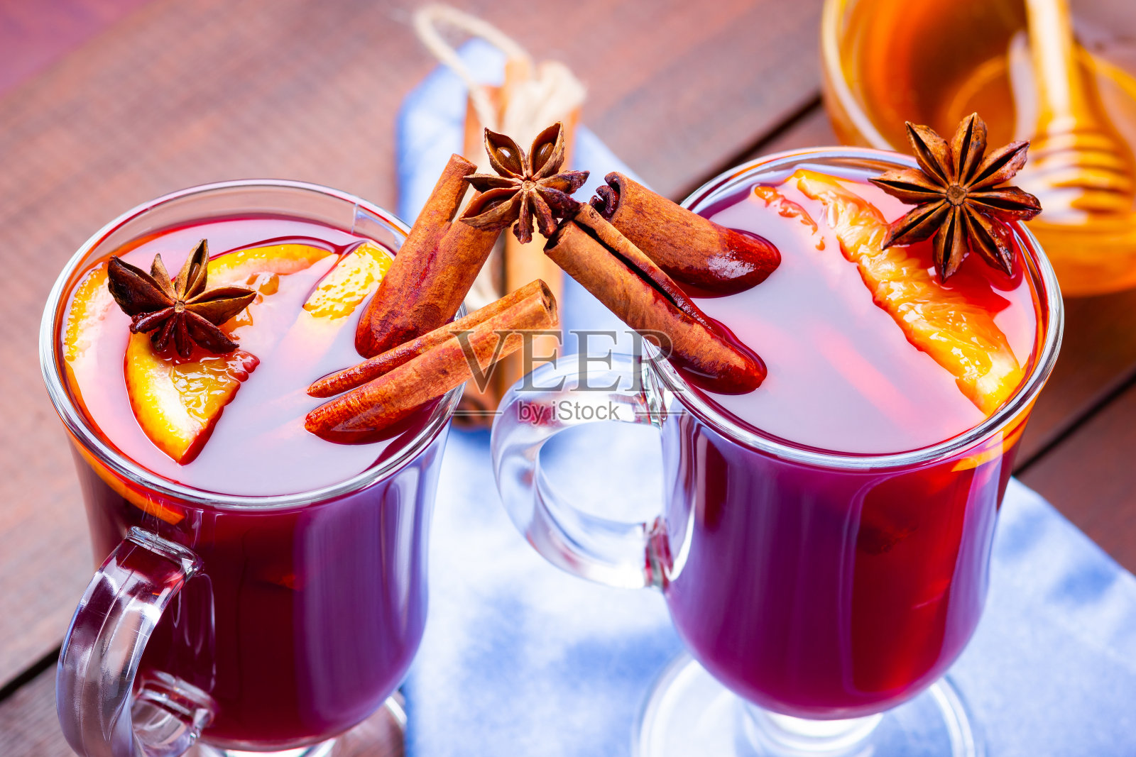 加香料和蜂蜜的热葡萄酒，木质背景。橘子，八角和肉桂的圣诞热葡萄酒。蓝色餐巾上放着两杯热红酒照片摄影图片