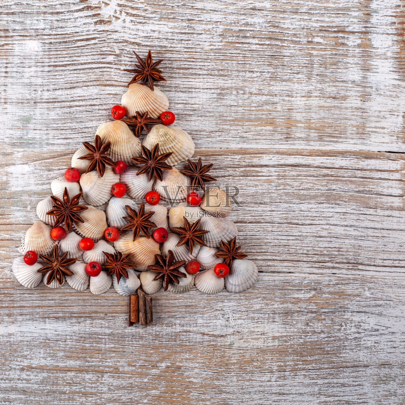 圣诞树由不同类型的海贝和海星制成，以木制为背景。像圣诞树一样的贝壳。新年庆祝概念照片摄影图片