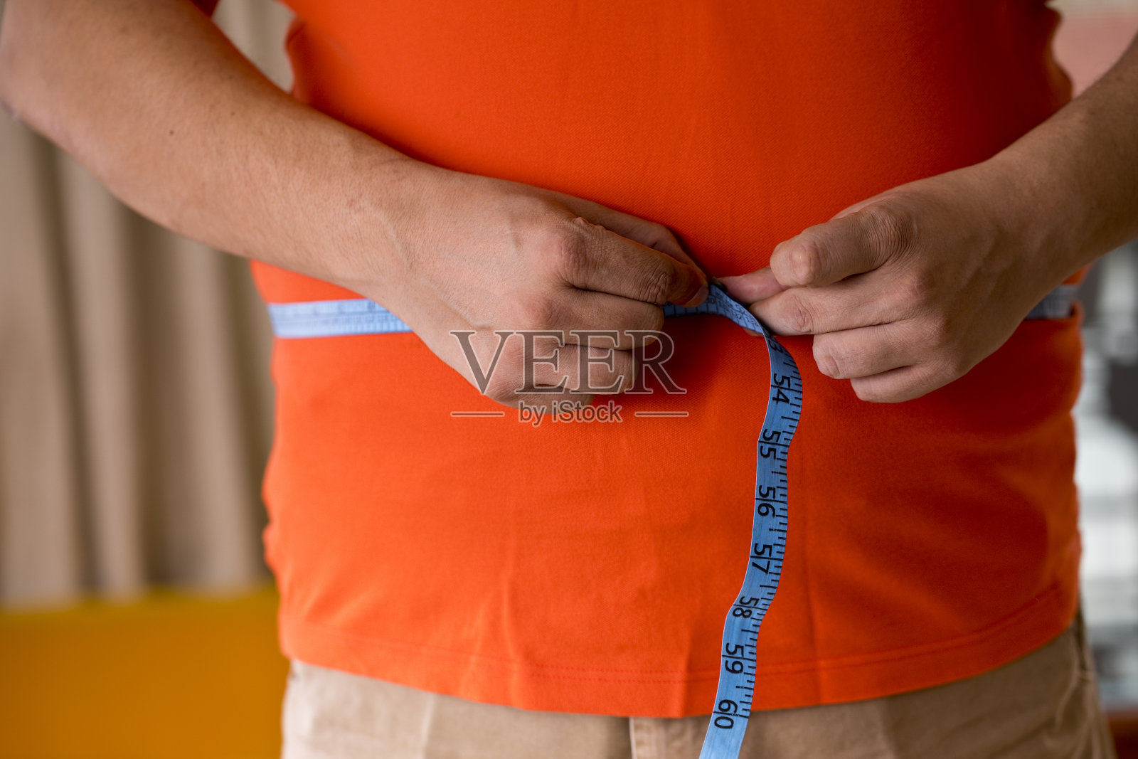 一个肥胖的男人在测量他的肚子照片摄影图片