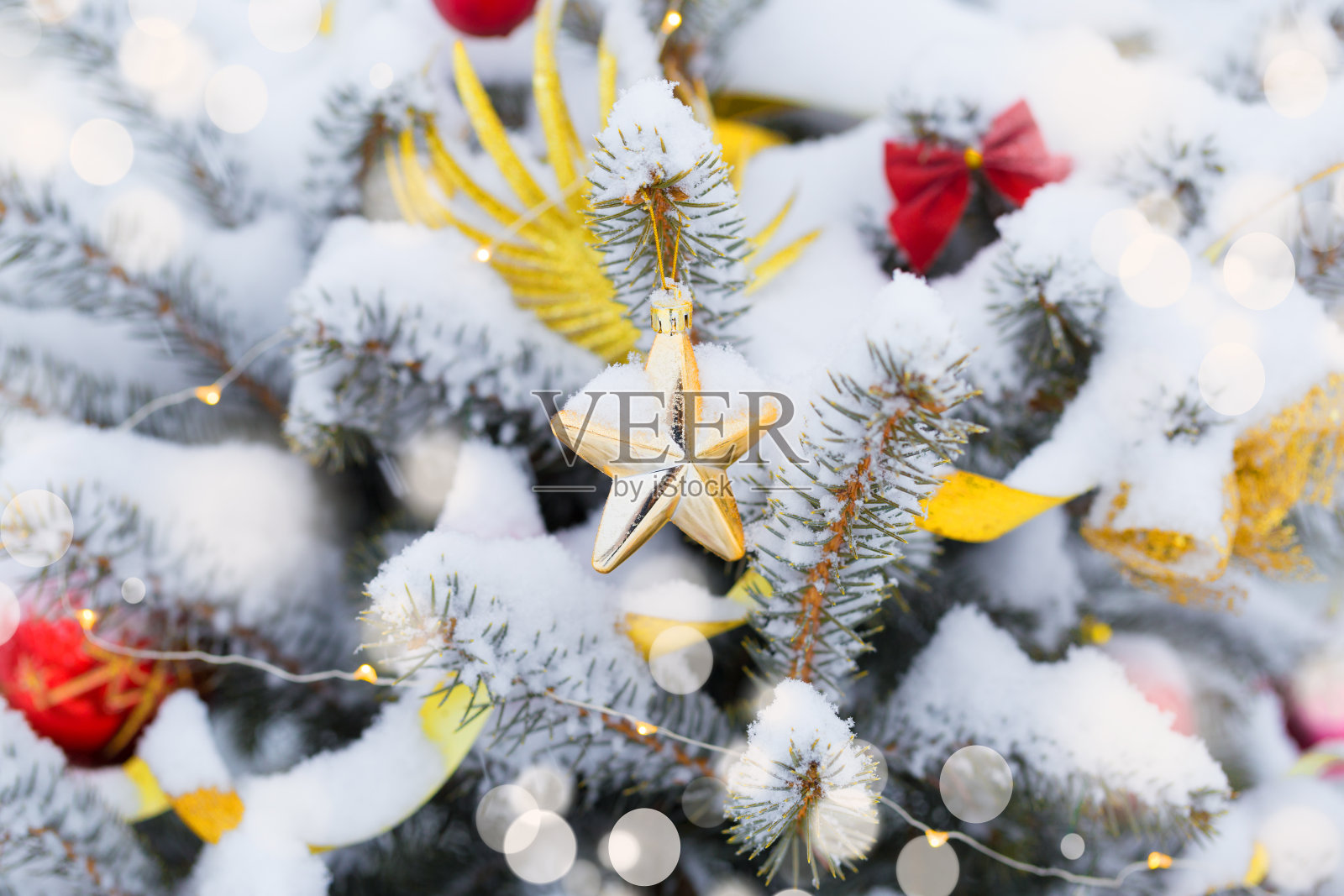 圣诞树在雪的背景。新年的组成与冷杉树，球，灯和散焦。照片摄影图片