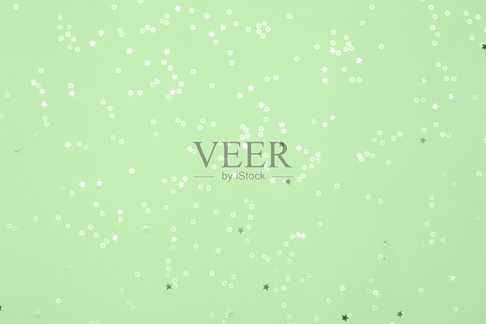 薄荷背景上点缀着薄荷五彩纸屑、星星和闪光。照片摄影图片