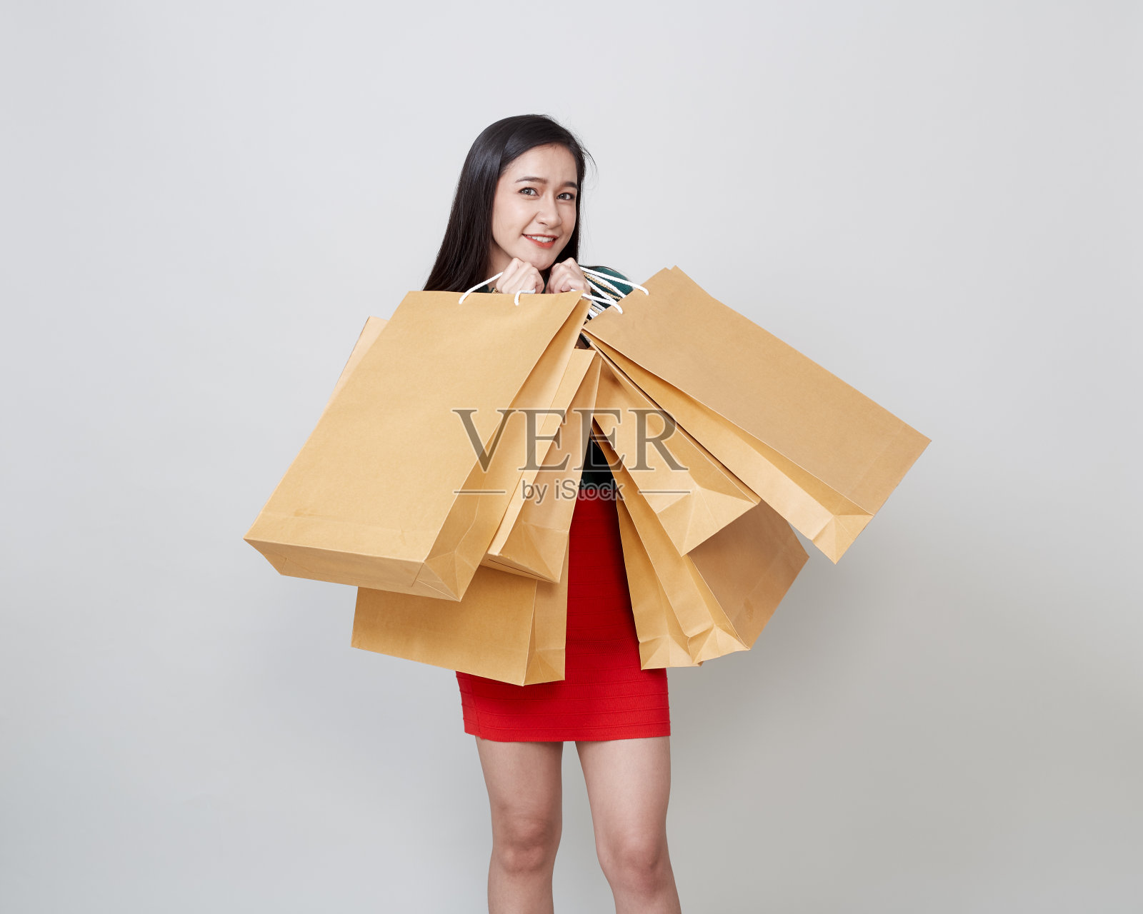 美丽快乐的圣诞节亚洲女人购物纸袋在明亮的灰色背景照片摄影图片