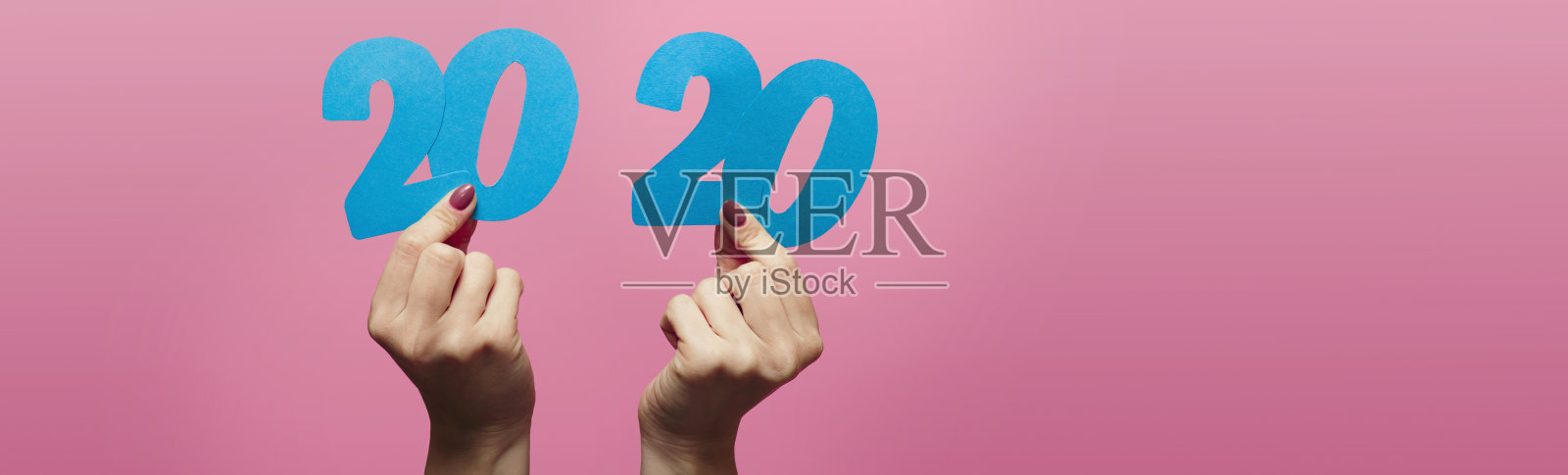 女性手牵着手，在粉色背景上用纸板剪出2020年的日期，概念新年，创意创意照片摄影图片