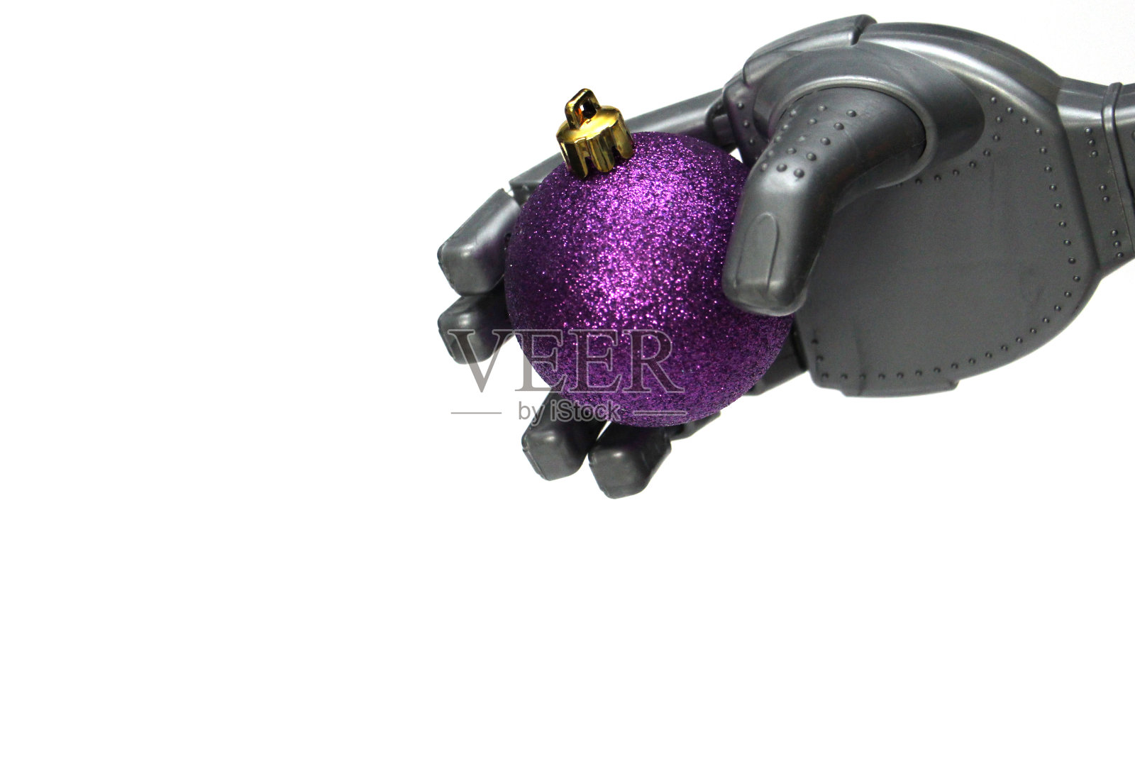 一个机器人手里拿着一个紫色的圣诞树装饰品。照片摄影图片