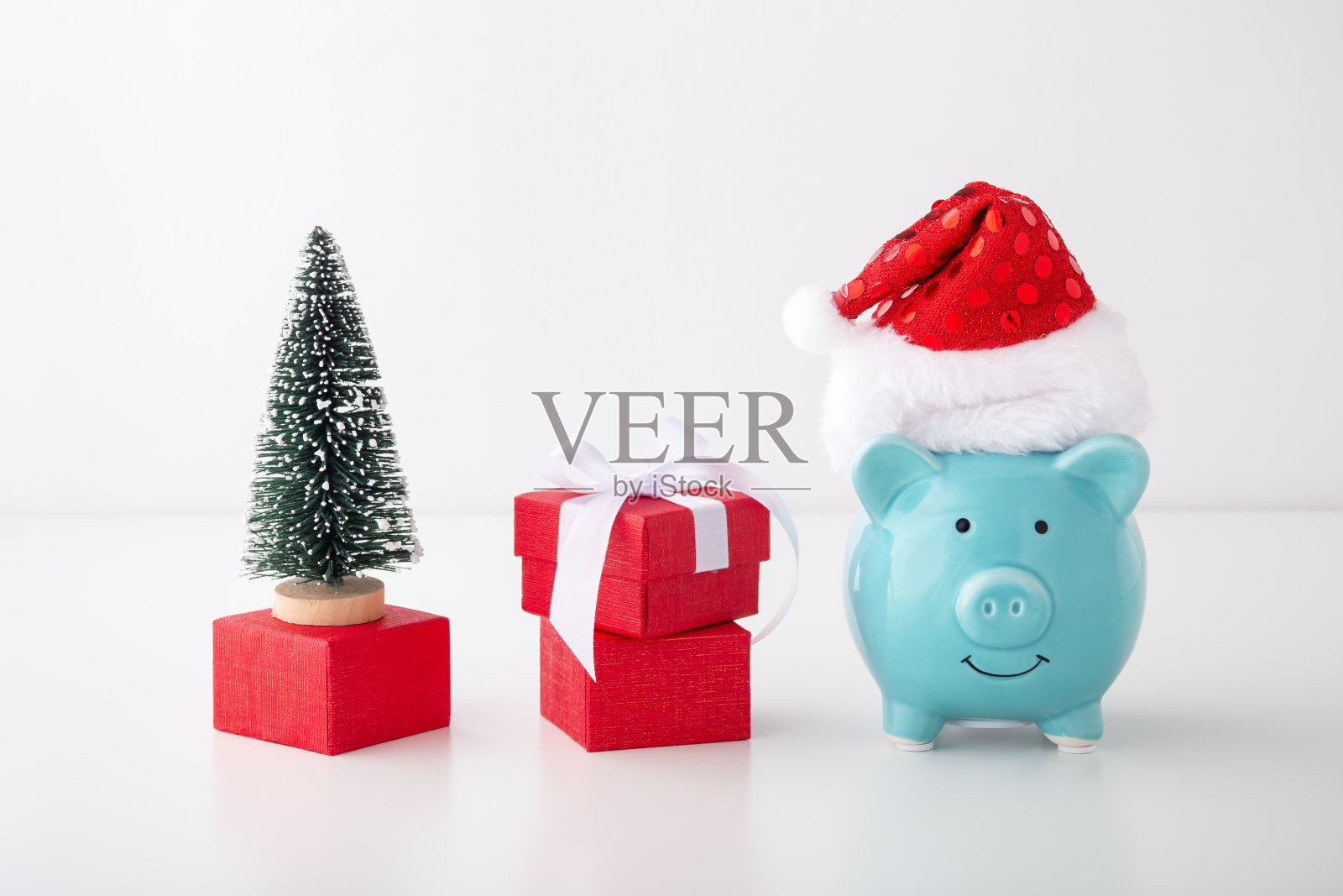 有圣诞帽的储蓄罐，礼品盒，圣诞树照片摄影图片