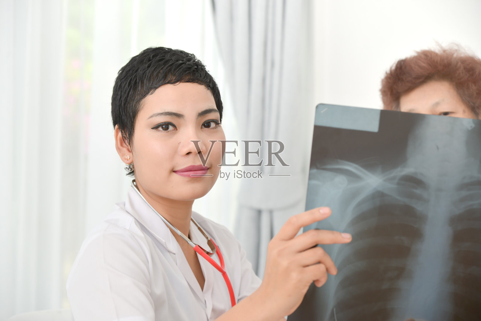 医生给一位老年妇女看x光结果照片摄影图片