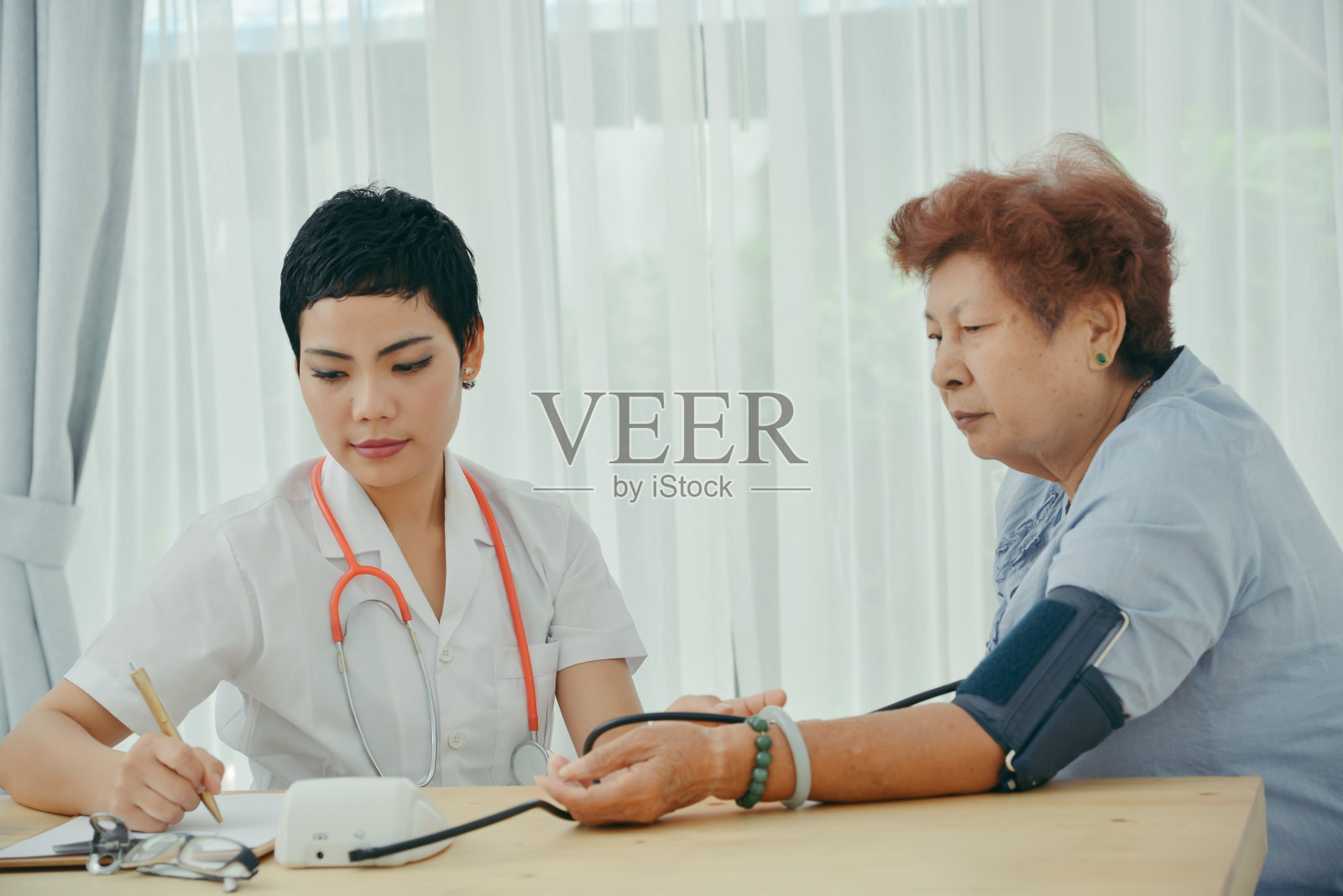 亚洲医生检查她的病人女性在办公室。照片摄影图片