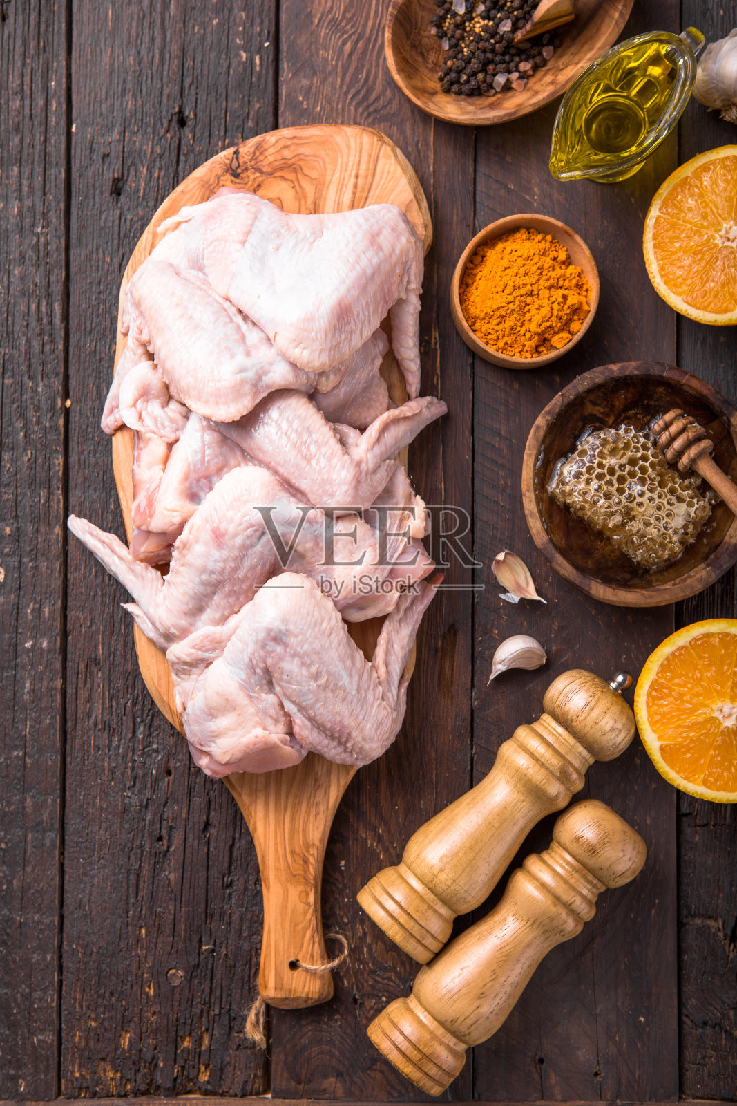 生鸡翅和烹饪材料:嘿，橘子，大蒜，橄榄油，木砧板上的卡里木背景。前视图。照片摄影图片