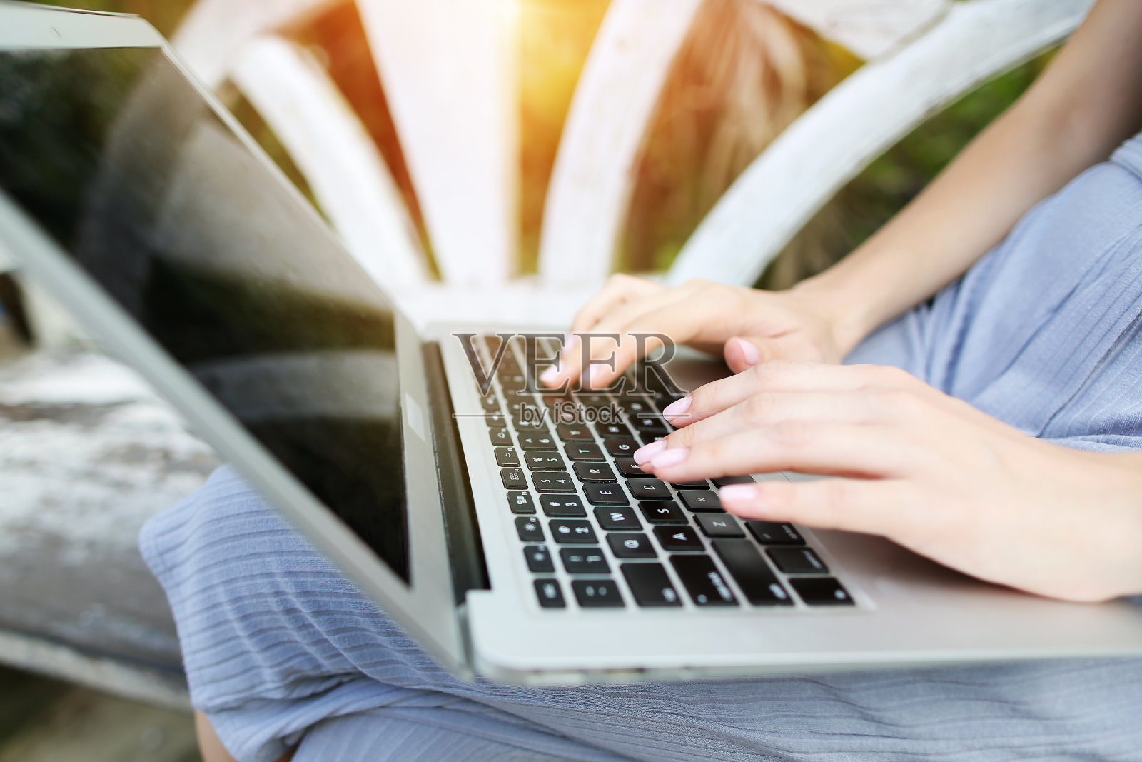 近距离的年轻女子双手手指按着笔记本电脑键盘进行远程工作，在阳光明媚的日子里，背景是泰国普吉岛的绿色棕榈树旅游照片摄影图片